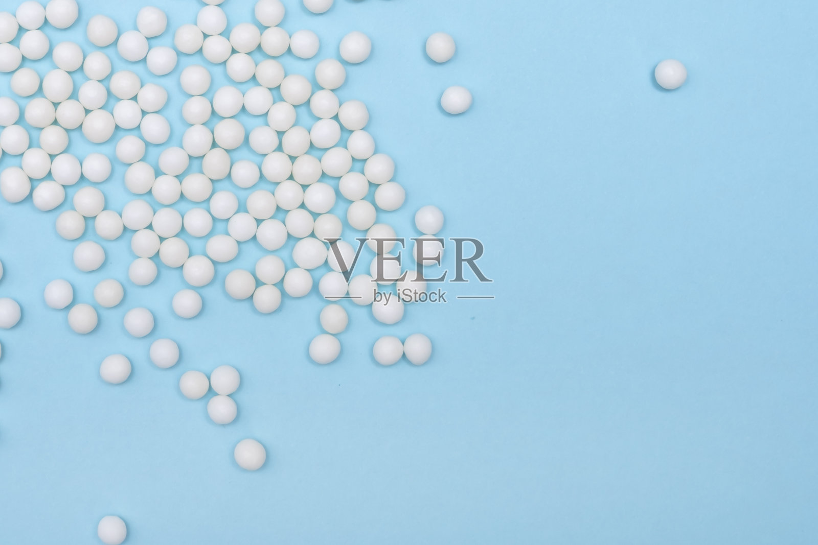 散落在淡蓝色背景上的许多顺势疗法小球，替代疗法医学概念，特写带复制空间照片摄影图片