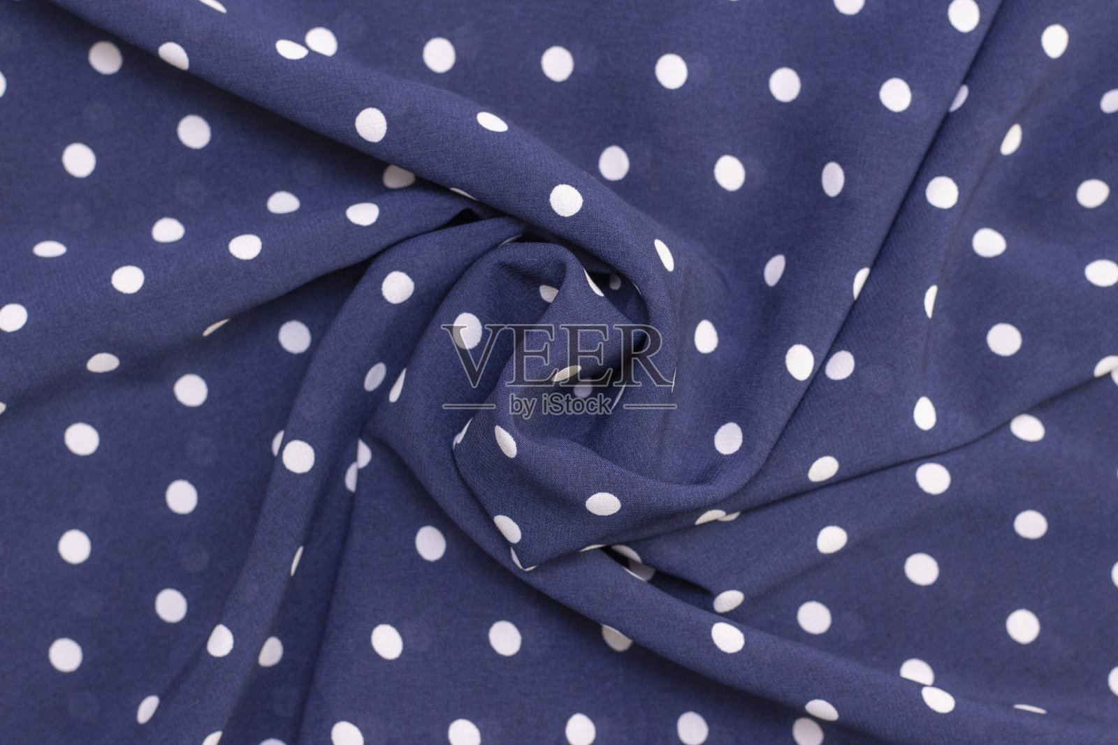 美丽的扭曲织物在一个图案与白色波尔卡点在深蓝色的背景。织物背景纹理照片摄影图片
