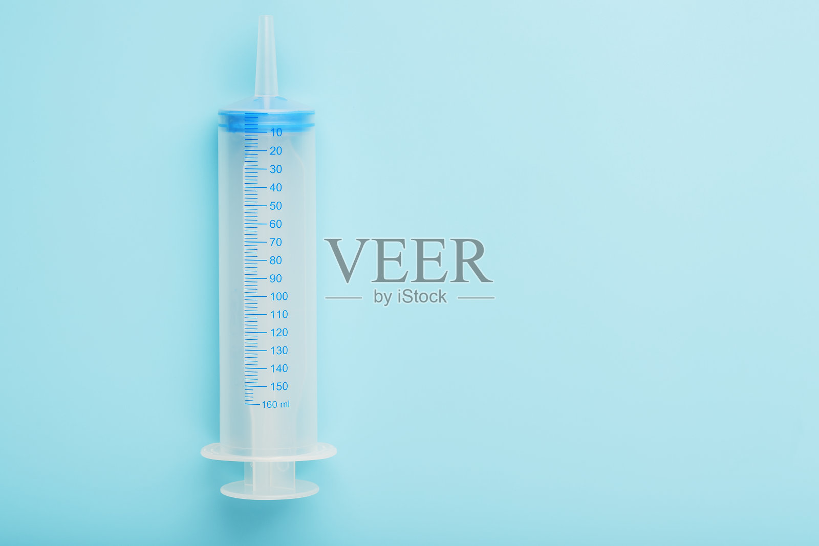 蓝色背景上的大型医用注射器，极简主义概念照片摄影图片