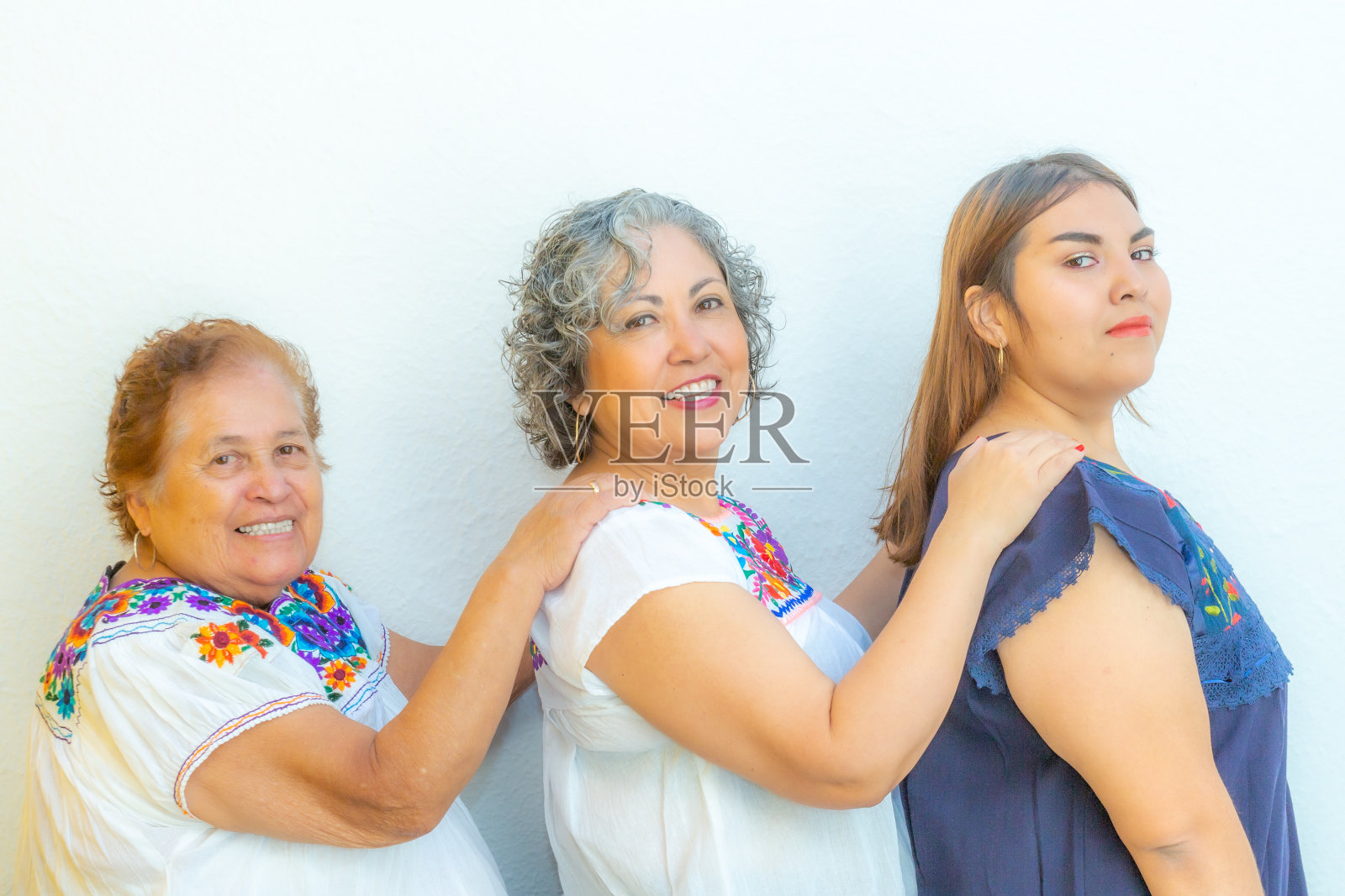 一代又一代笑容满面的墨西哥妇女穿着一排印花衬衫挽着她们的肩膀照片摄影图片