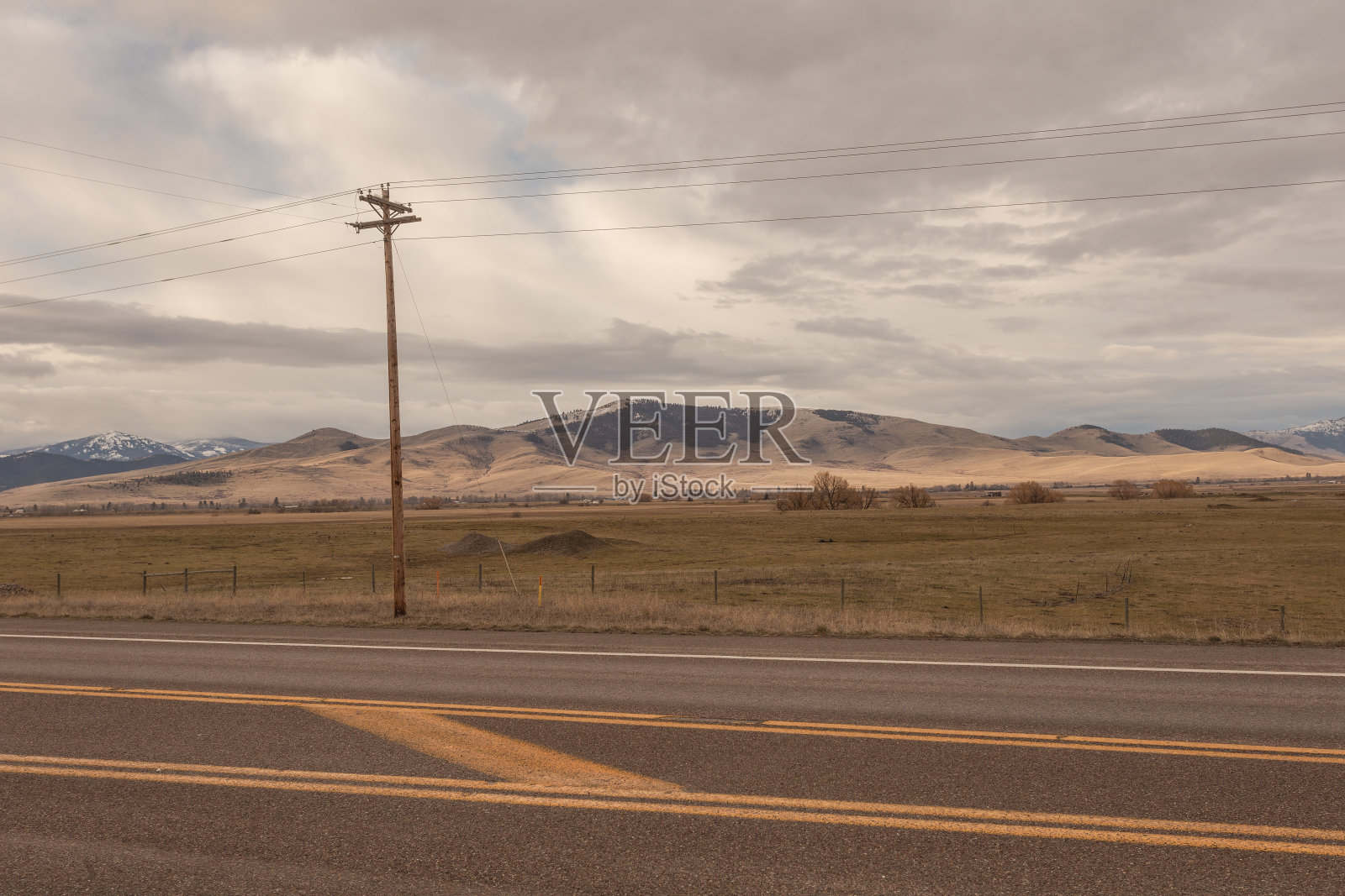 空空如也的高速公路旁的电线杆，远处连绵起伏的山峦照片摄影图片