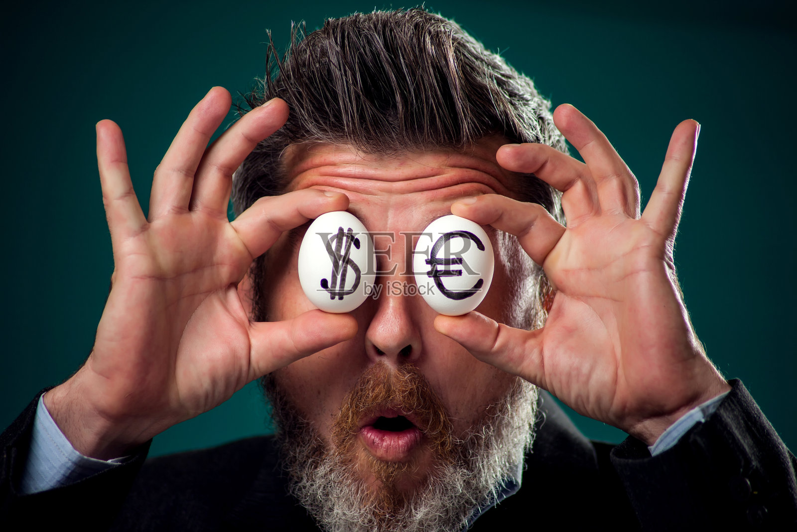 西装革履的男人拿着画着美元和欧元符号的白色鸡蛋的肖像，商业和金融概念照片摄影图片