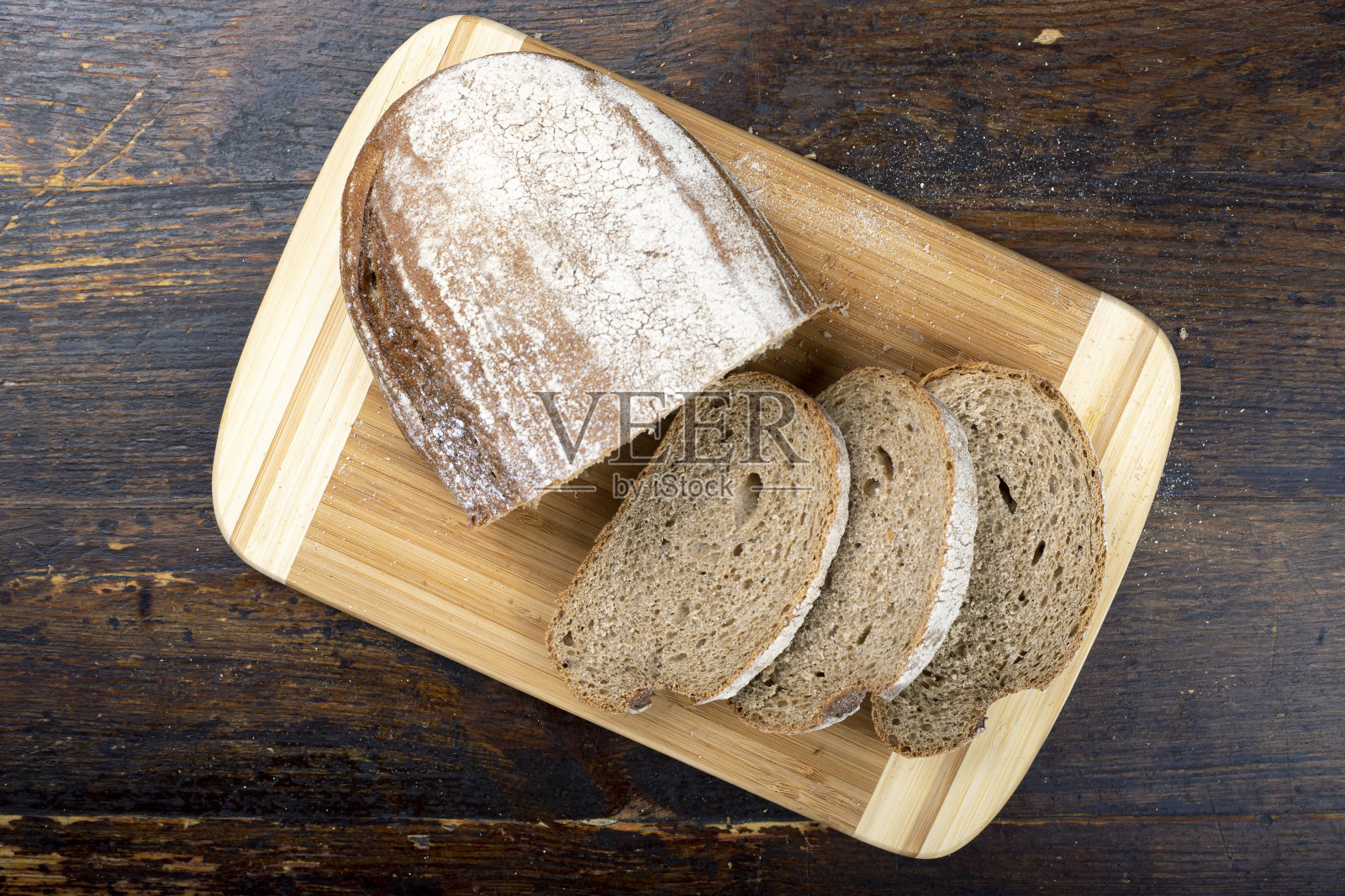 把新鲜的面包切成片放在砧板上。照片摄影图片