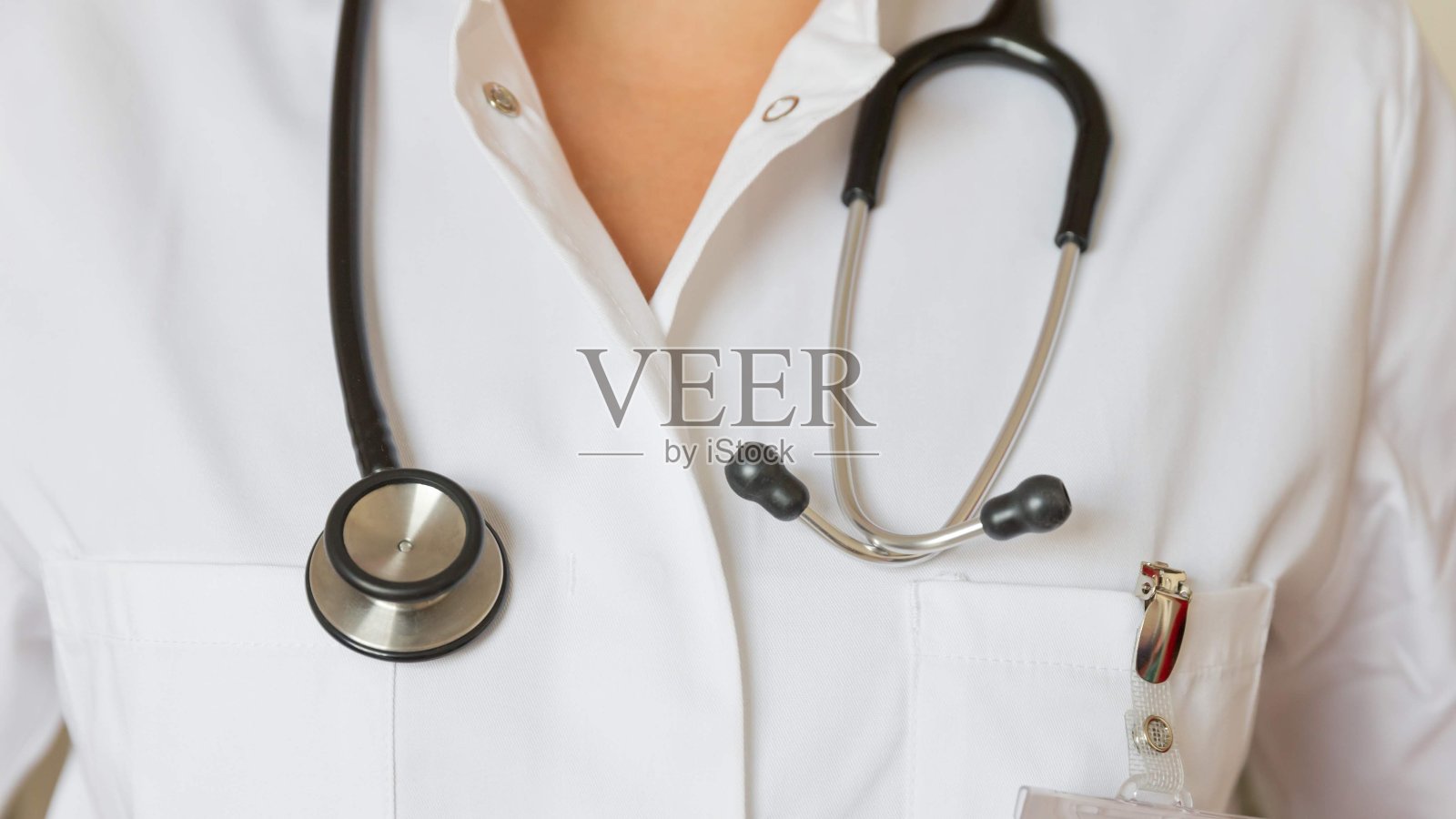 年轻女性医学博士，身穿白色制服，佩戴警徽和听诊器照片摄影图片