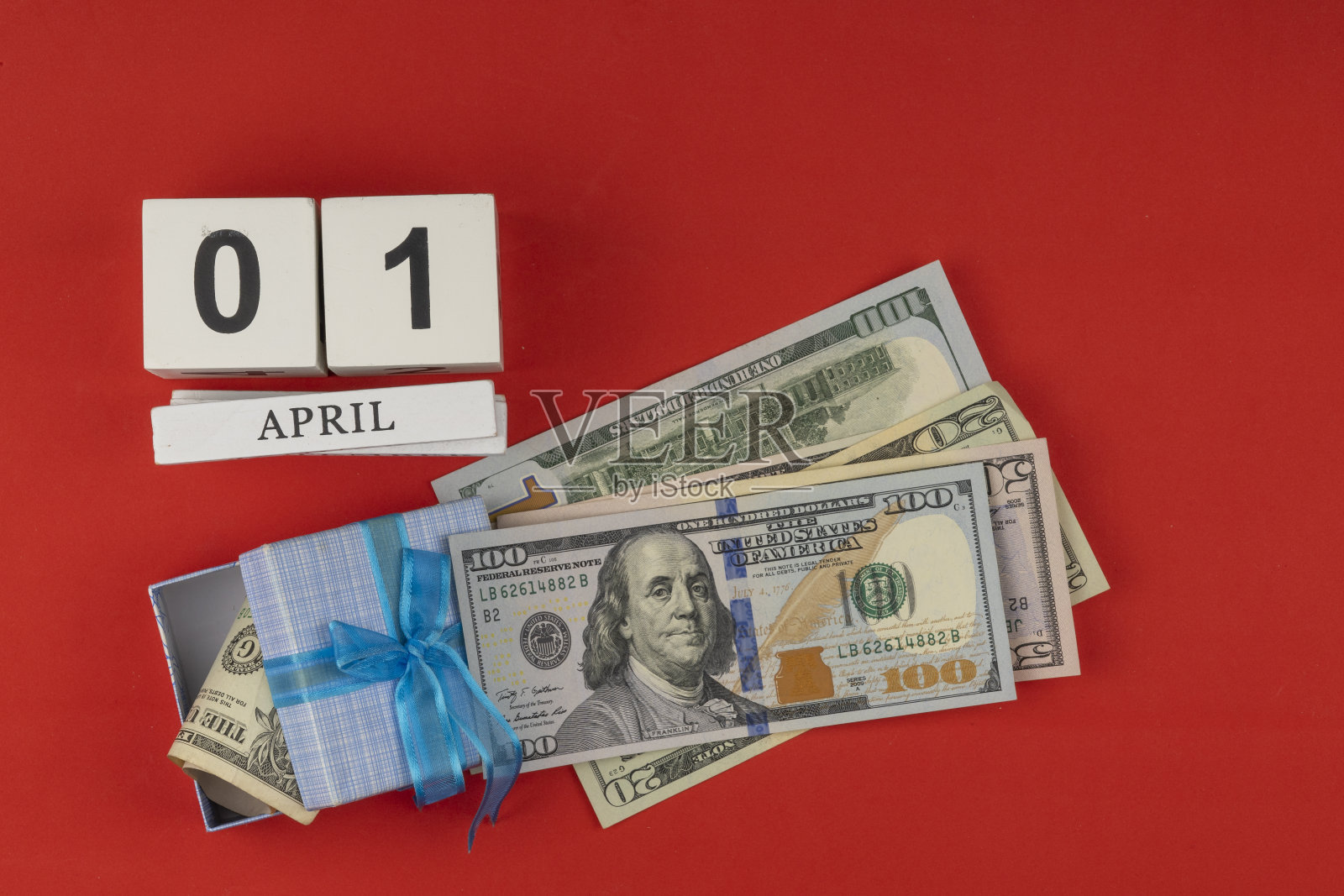 木制立方体的万年历。在4月1日庆祝美元生日的概念。美元系着节日的蝴蝶结。美国货币，纸币。红色节日背景照片摄影图片