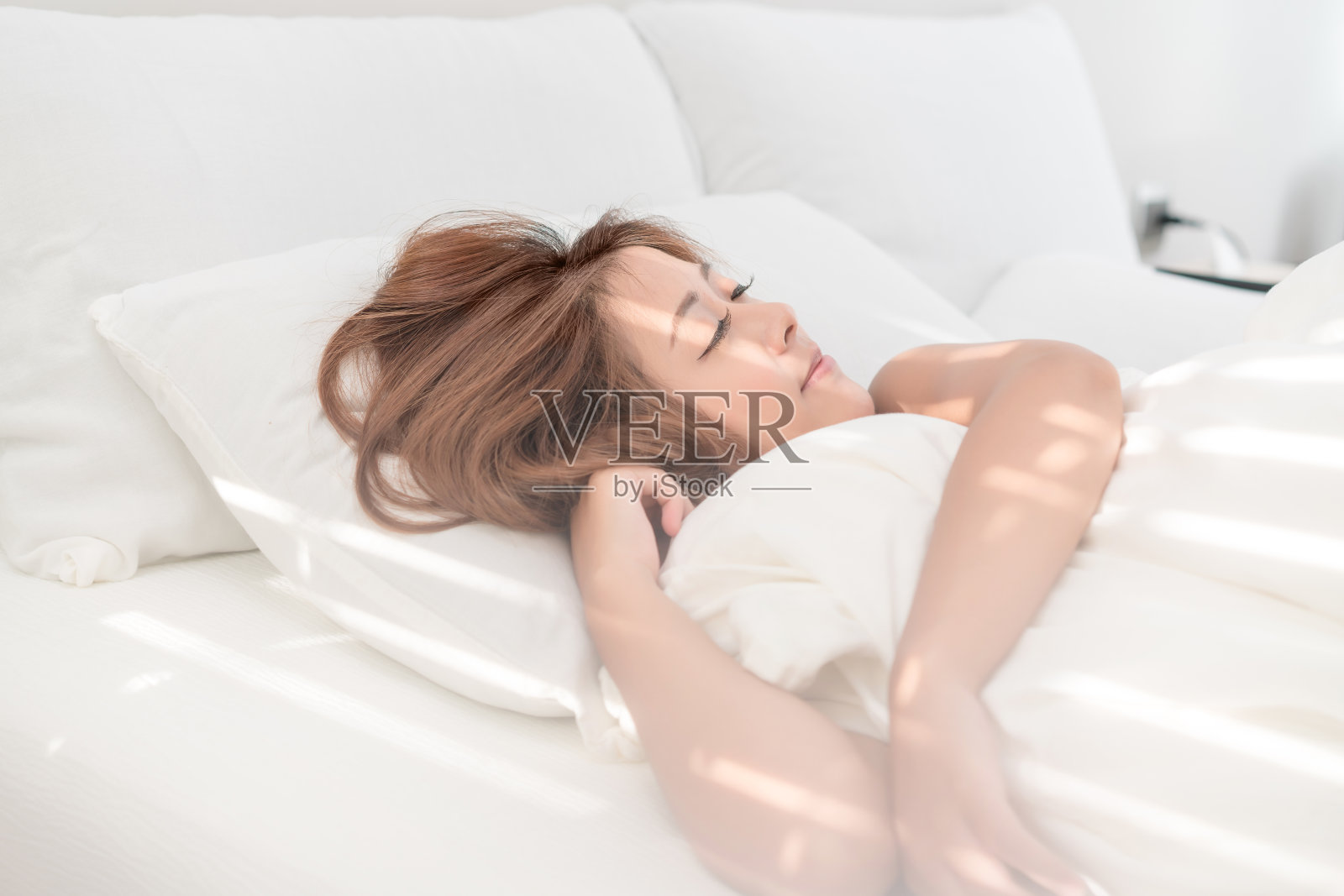 美丽的亚洲女人肖像与迷人的微笑享受新鲜柔软的床上用品亚麻布床垫在白色的卧室现代公寓。可爱的亚洲女孩睡觉休息，晚安睡眠的概念。照片摄影图片