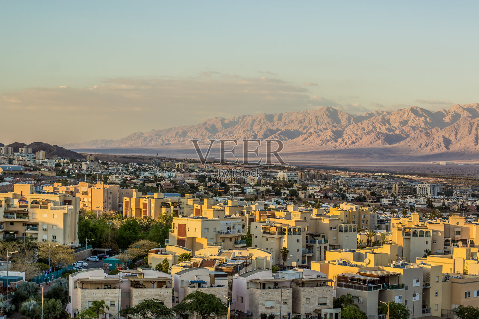以色列埃拉特市位于中东亚喀巴湾地区，城市地标景观小生活建筑和沙漠山脊背景景观如画的景色在夕阳黄色的灯光照片摄影图片