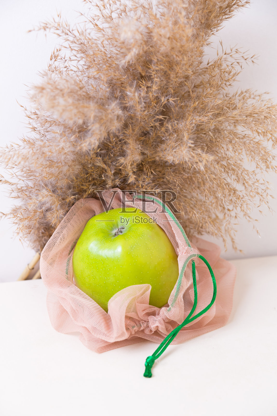 厨房桌子上的米色环保袋里的绿苹果。“零浪费”的概念照片摄影图片