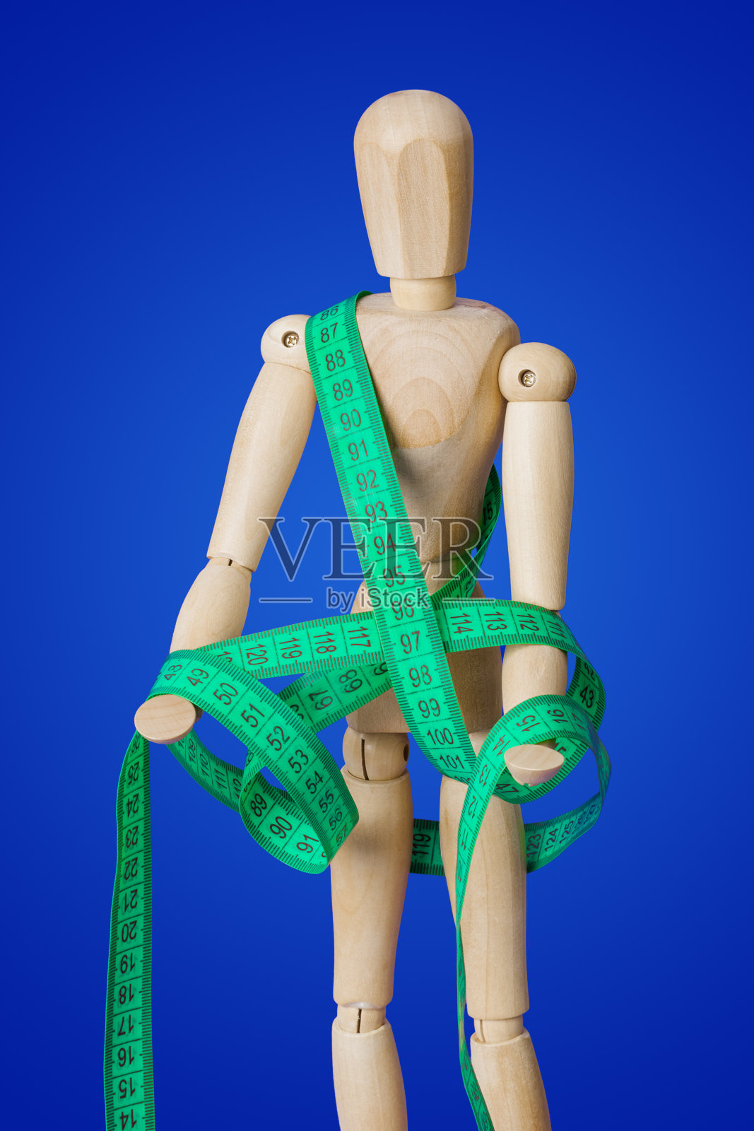 木制人偶在蓝色背景上拿着卷尺照片摄影图片