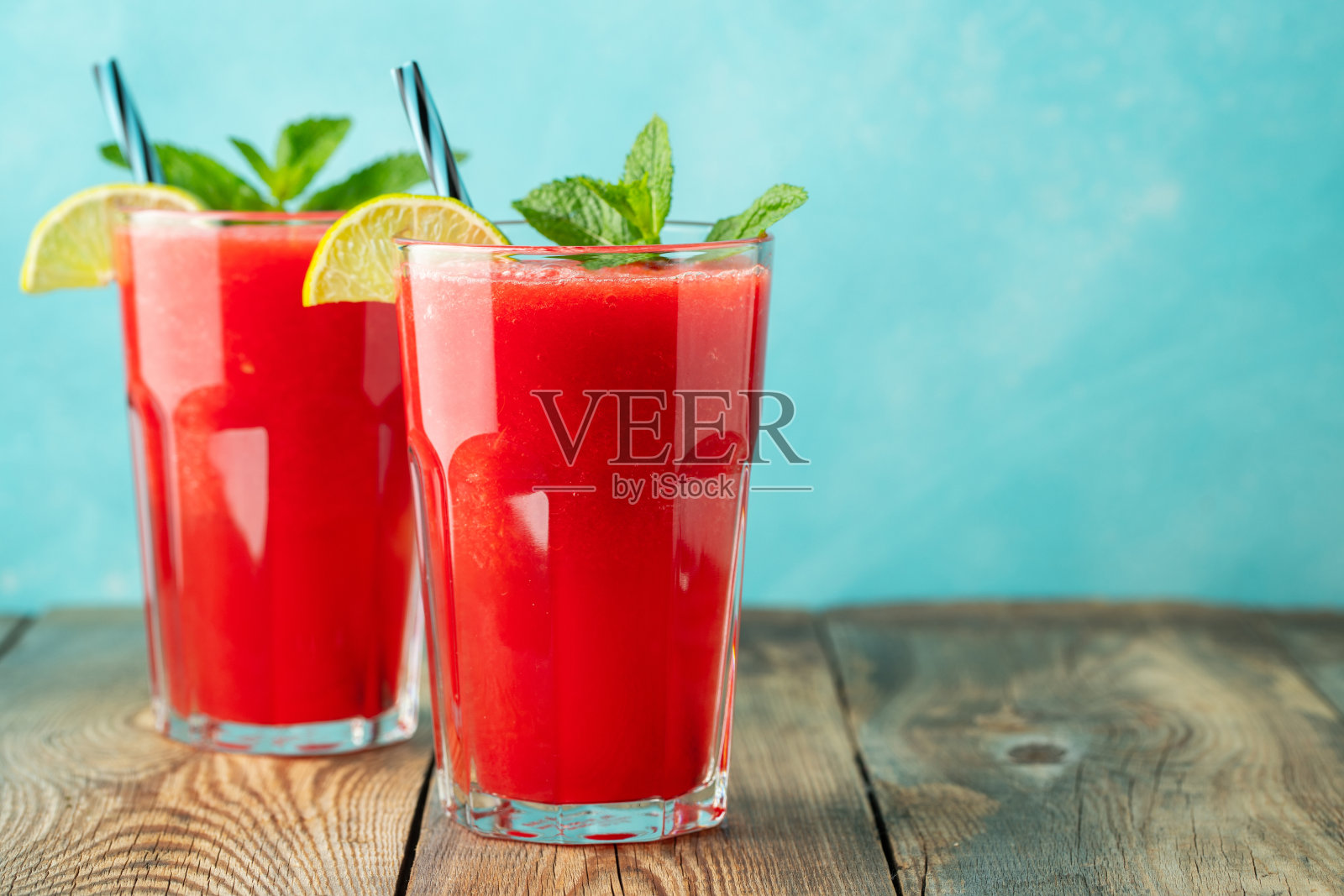 西瓜冰沙配柠檬和薄荷，在浅蓝色背景下的高脚杯中饮用夏日清凉饮品。甜冰沙与拷贝空间照片摄影图片