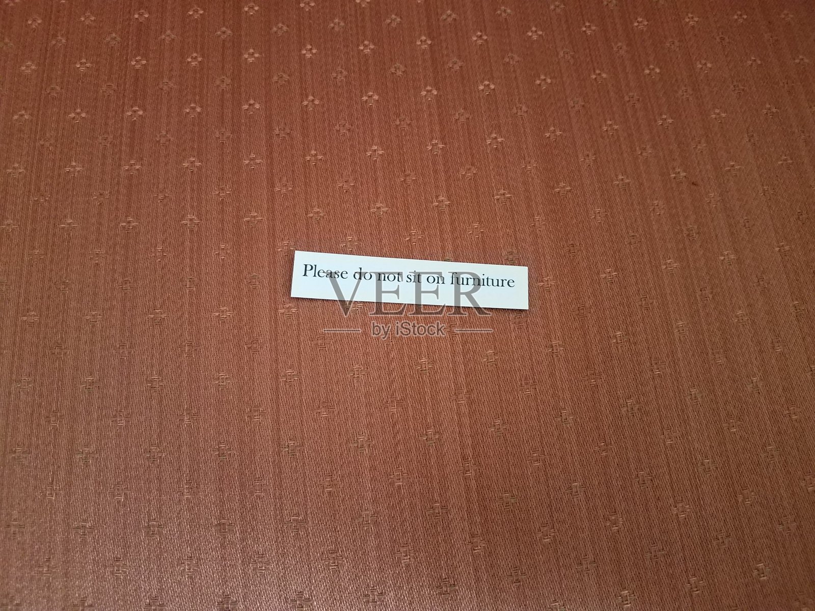 请不要坐在棕色织物上的家具标志上照片摄影图片