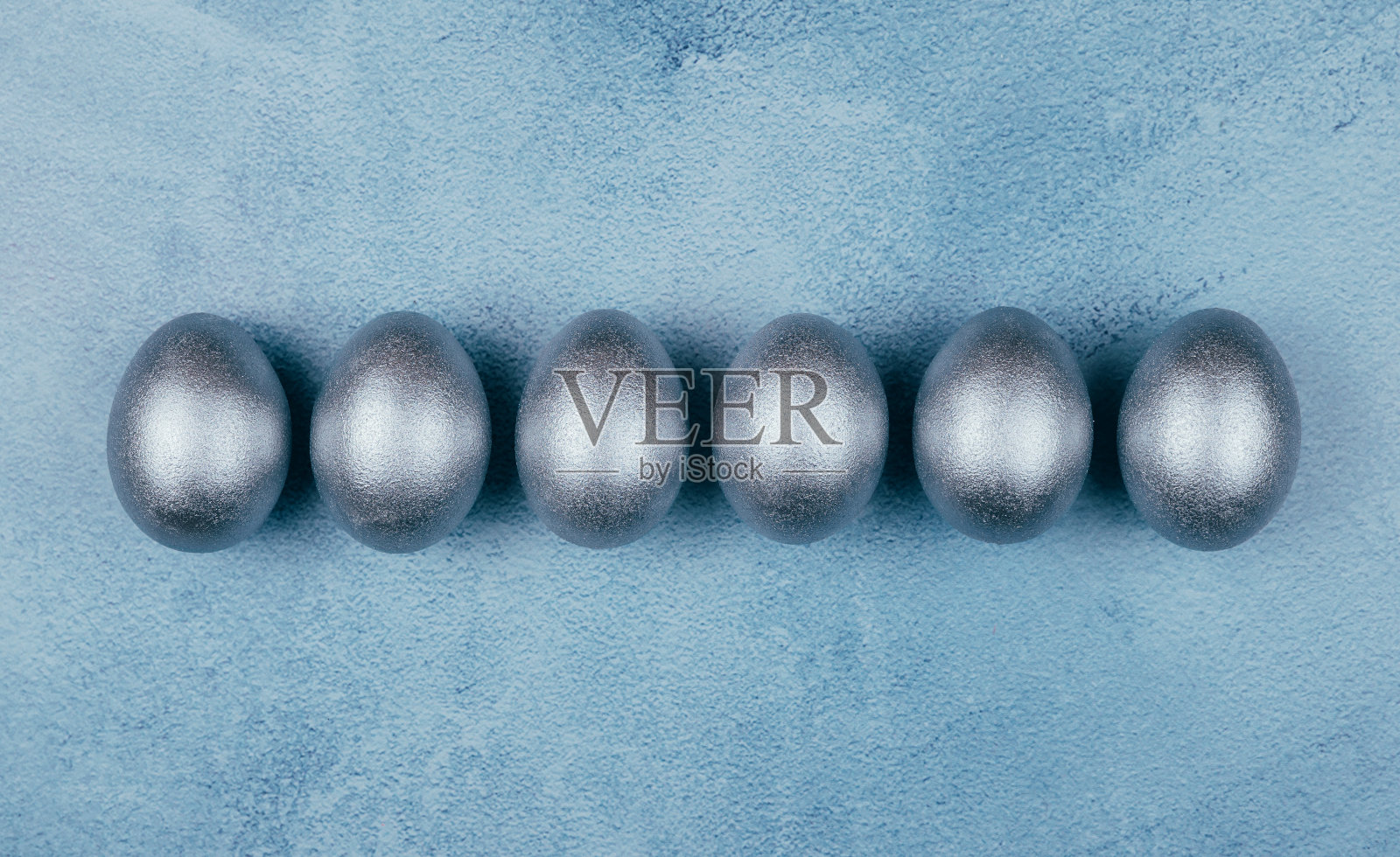 银灰色复活节彩蛋在一排纹理的蓝色背景。副本的空间。照片摄影图片