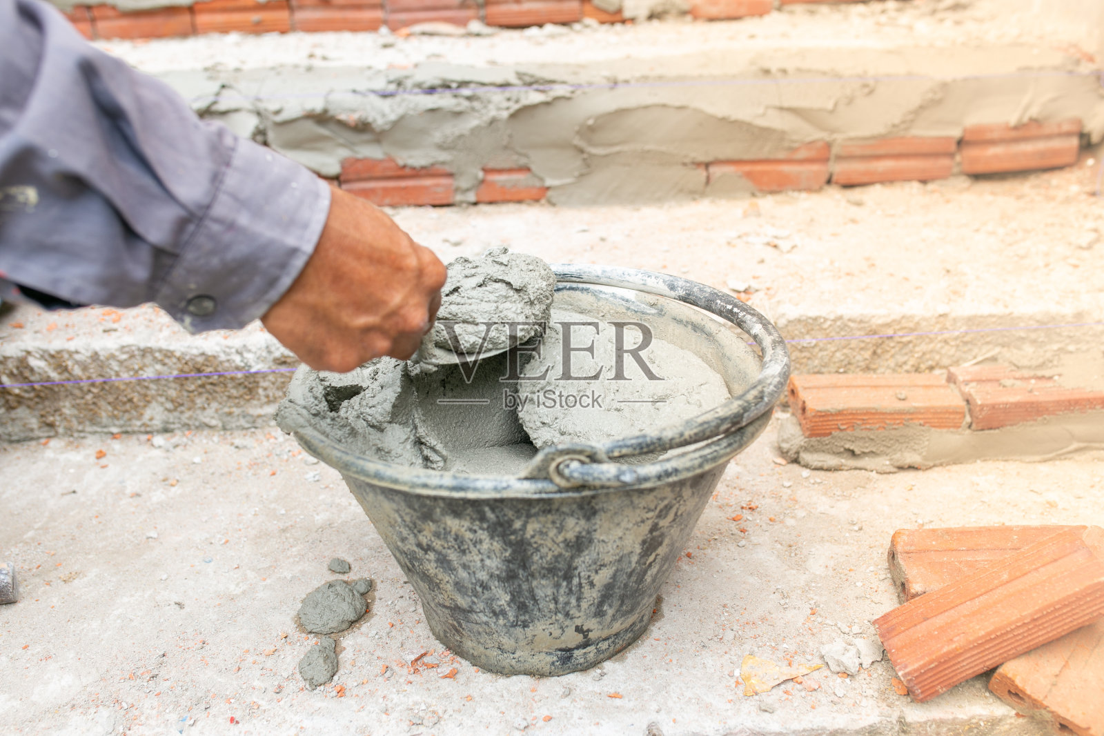 工人劳动，搅拌机操作员在建筑工地用混凝土水泥和砖砌楼梯。照片摄影图片