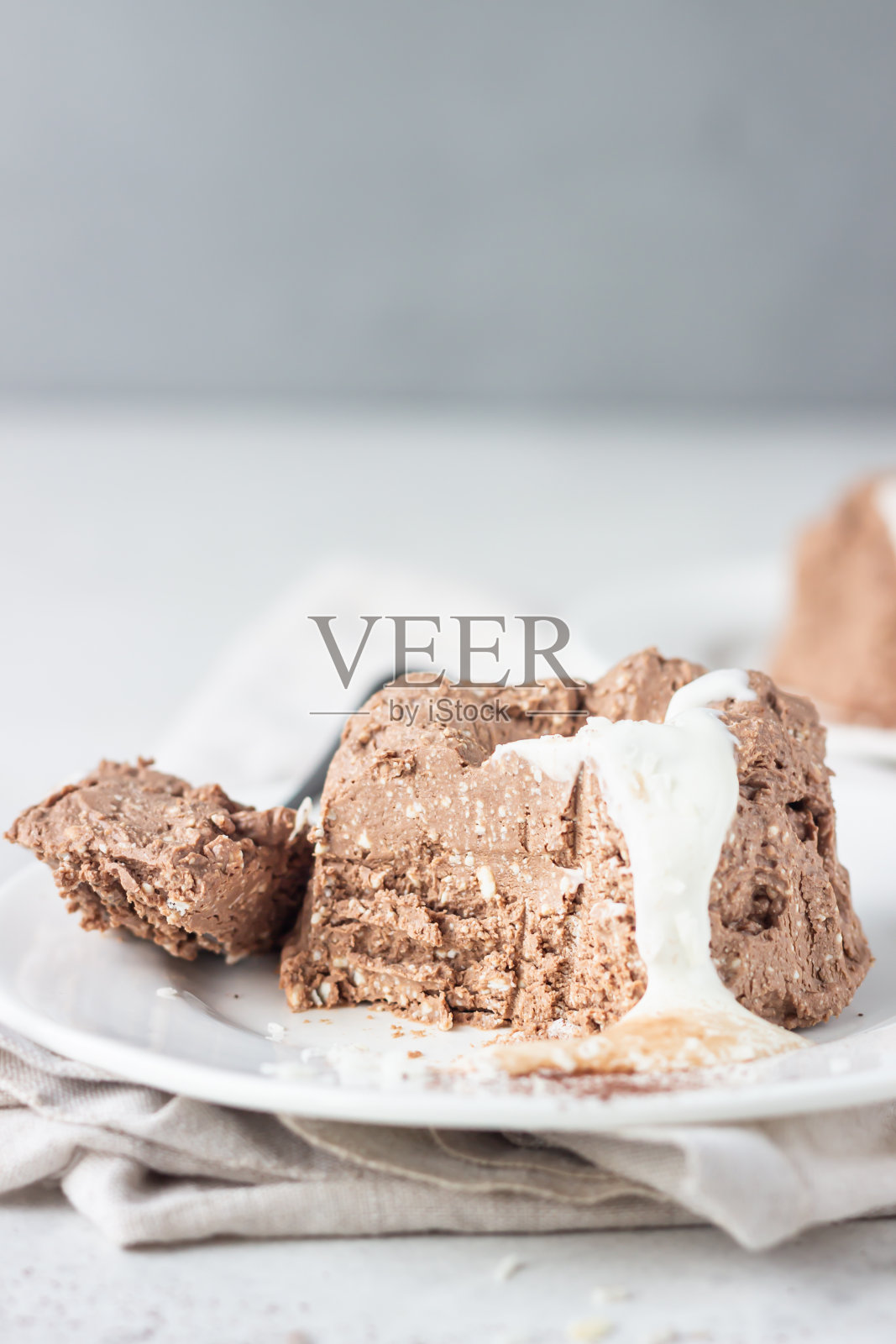 巧克力奶酪甜点装饰白巧克力釉，椰子片和可可粉，浅灰色的石头背景。照片摄影图片