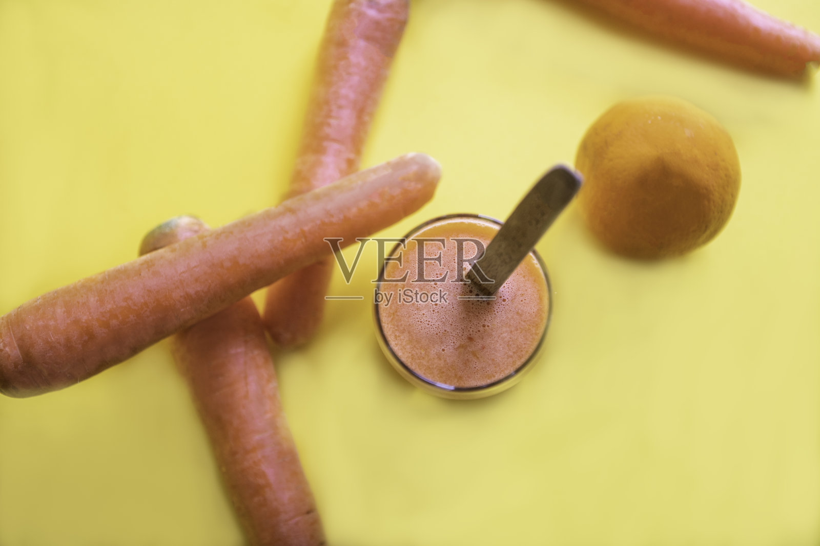 杯子里的果汁被新鲜的蔬菜和水果环绕在黄色的背景上照片摄影图片