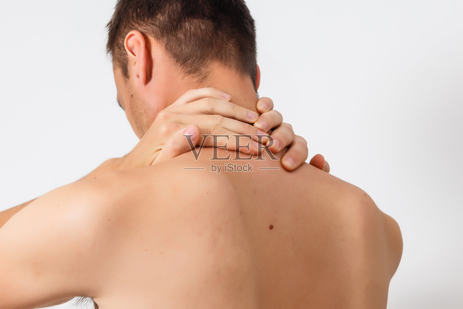 一名男子抱着受伤的脖子，孤立地站在白色背景上照片摄影图片