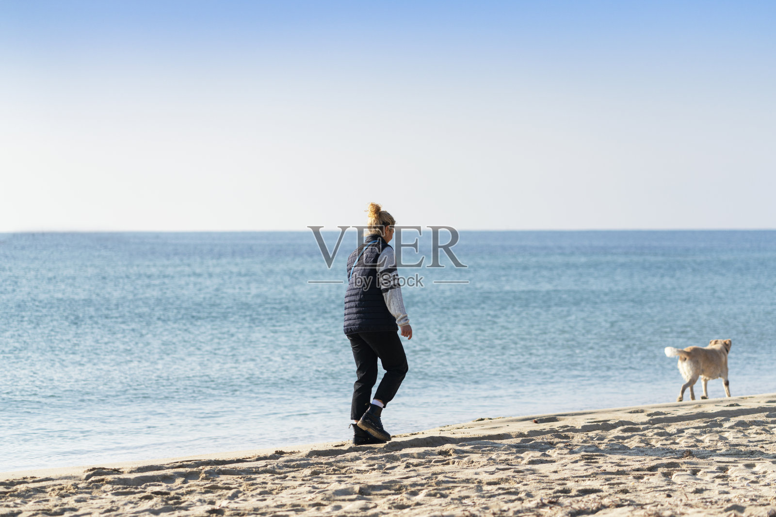 一个年轻女人和她的狗在海滩上照片摄影图片