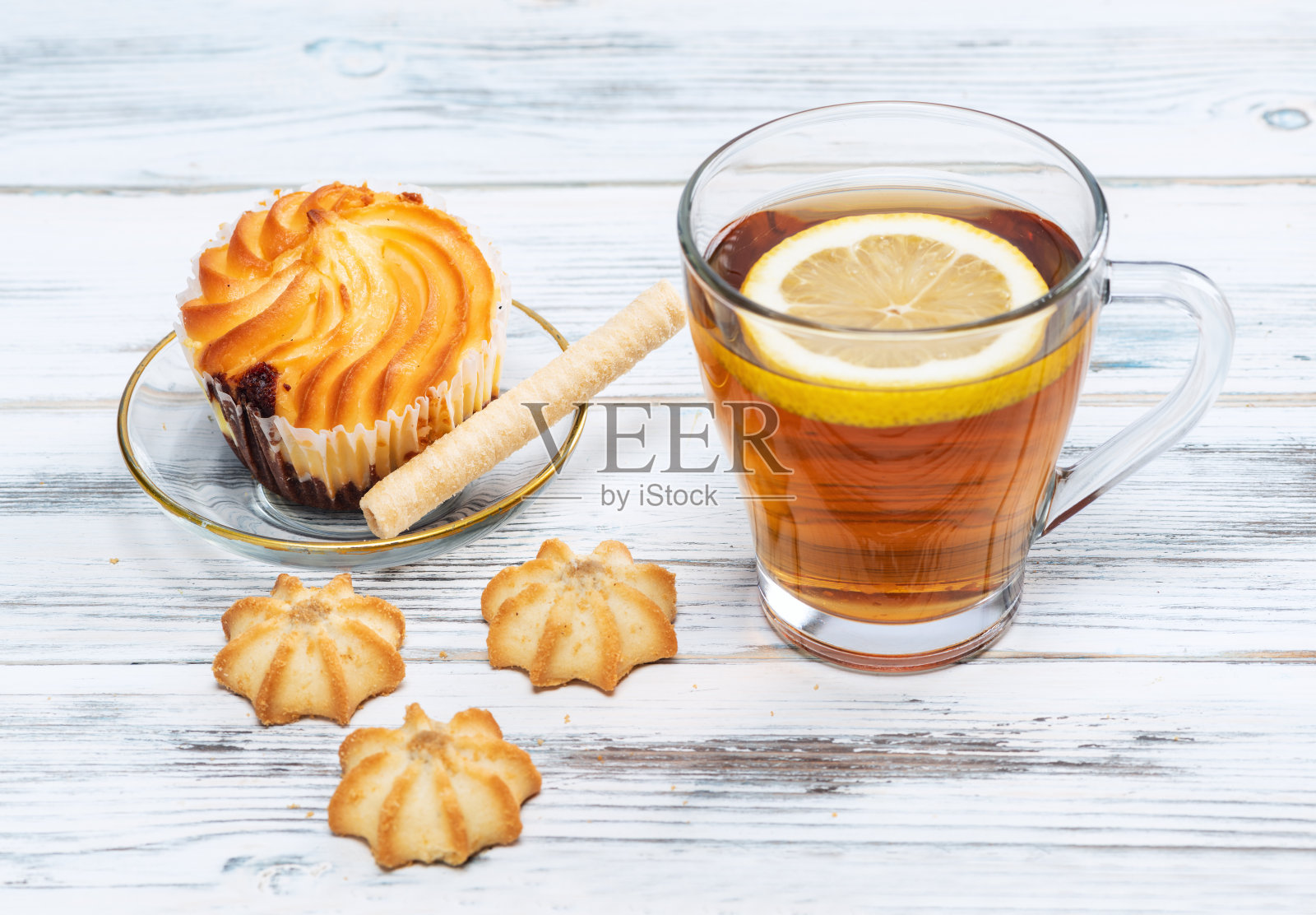 一杯配有柠檬和饼干的热茶，在白色的木制背景上。照片摄影图片