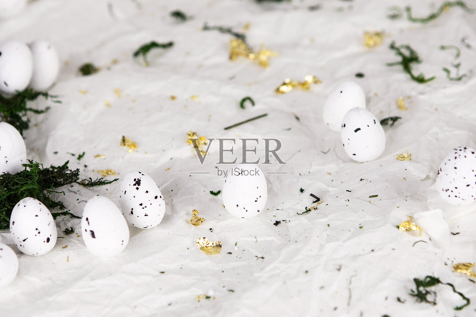 复活节彩蛋在皱巴巴的纸背景与苔藓和金色碎片。复活节装饰，季节背景。照片摄影图片