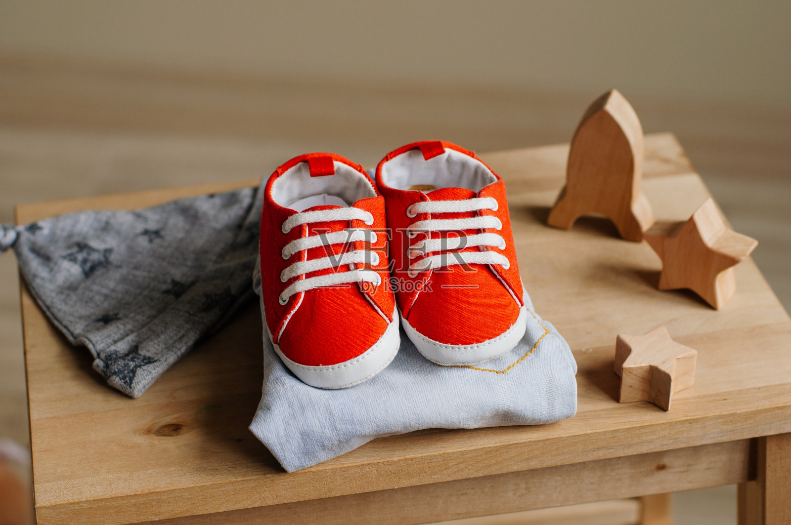 新生婴儿的鞋子、衣服和木制玩具躺在孩子的椅子上照片摄影图片