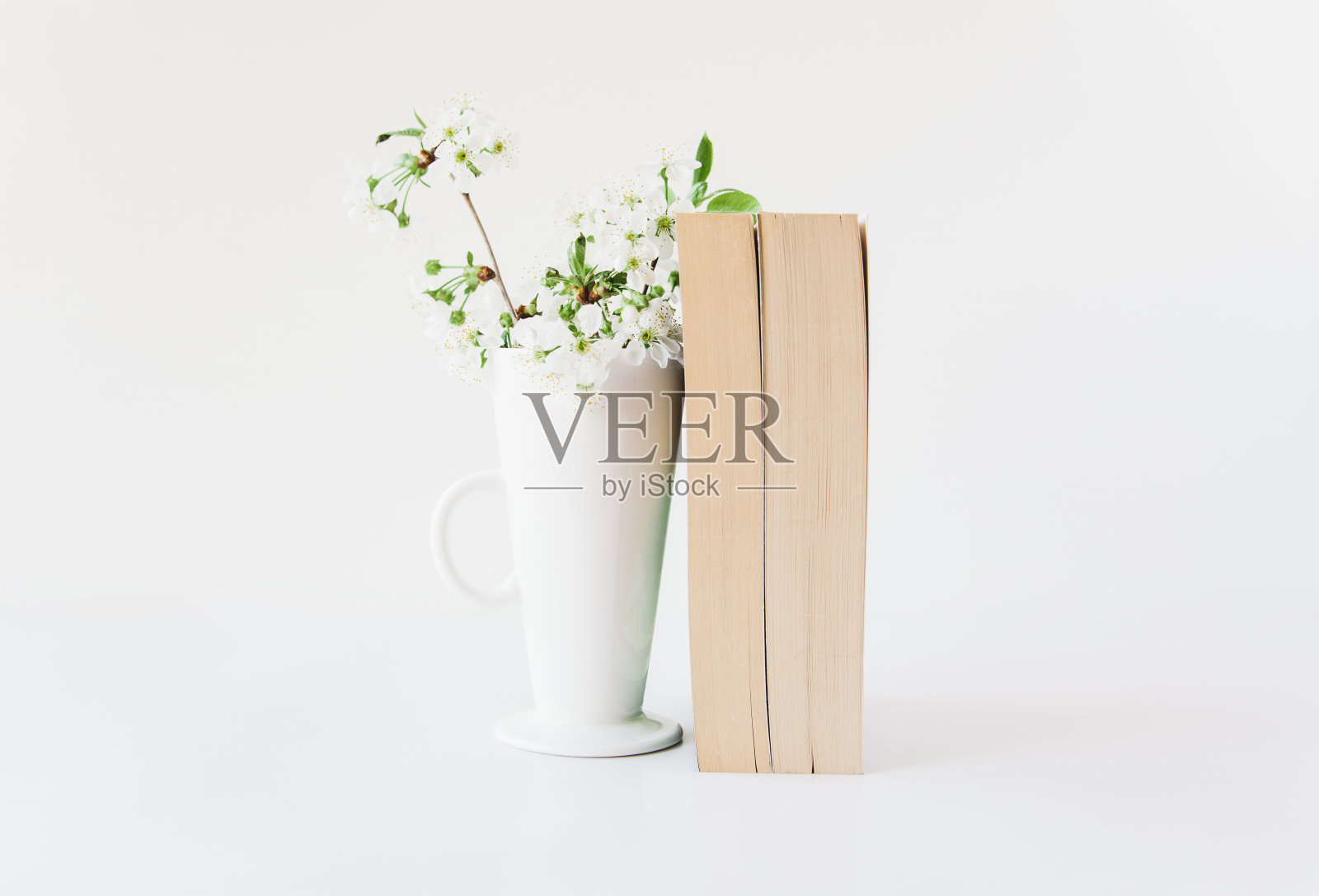 花瓶里有书和花。白色简约的背景。副本的空间。照片摄影图片