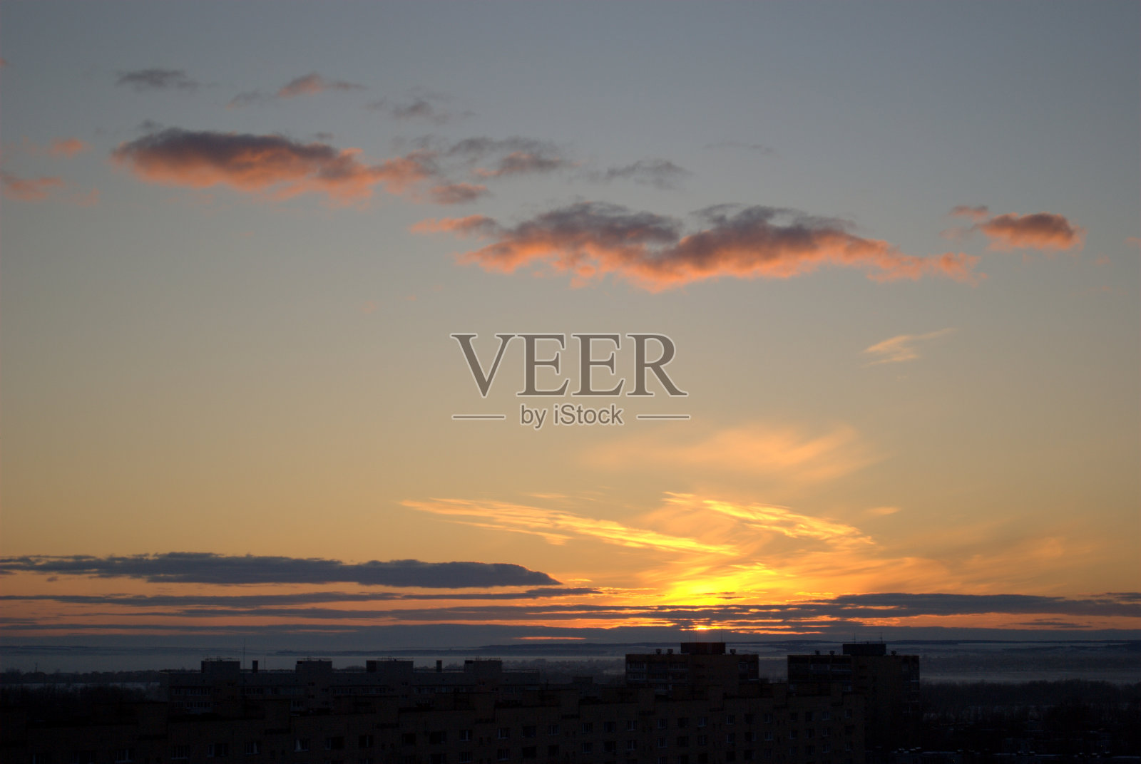 美丽的日落天空和小云照亮了城市的居民区的剪影。照片摄影图片