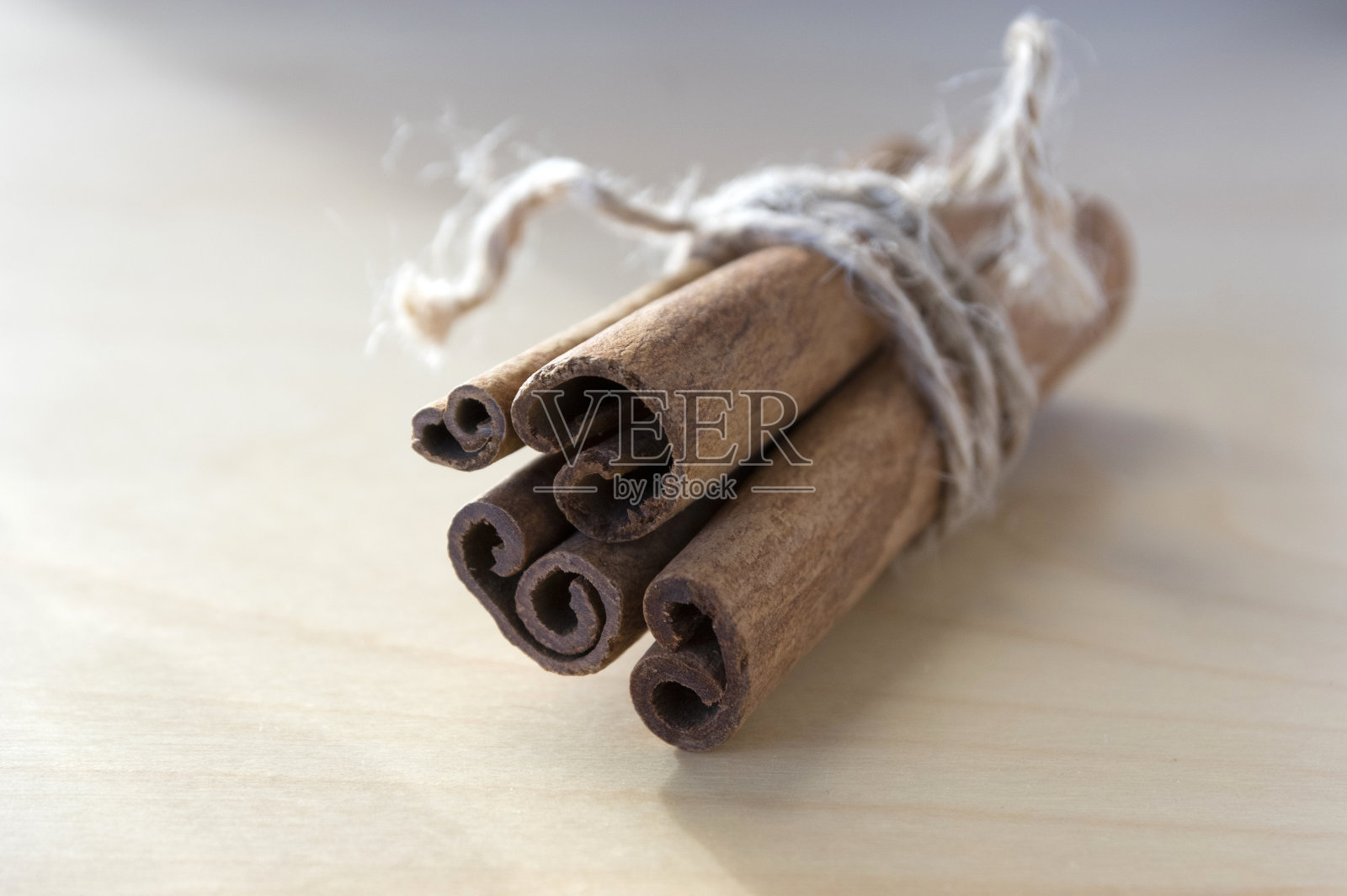 新鲜的生肉桂棒放在木桌上，用一根黄麻自然绳绑起来照片摄影图片