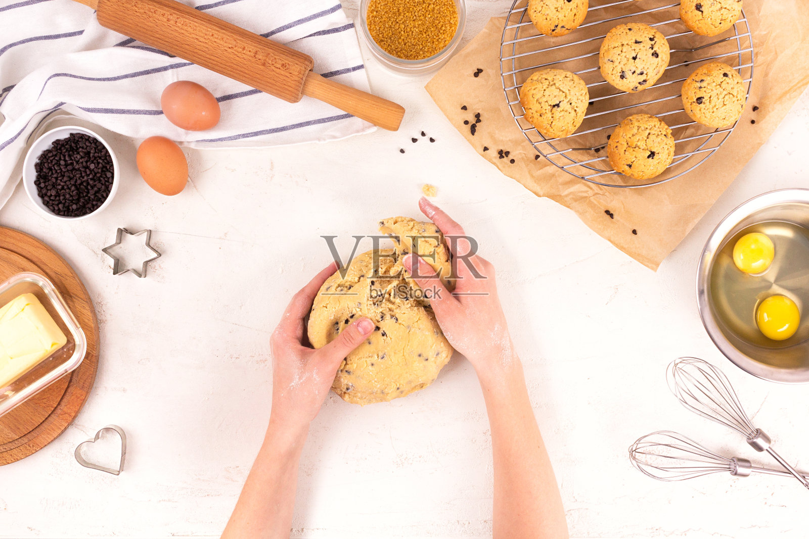 女人的手握着做饼干的面团。烹饪设备和配料。鸡蛋，面粉，糖，巧克力，黄油，烤盘。平的。照片摄影图片
