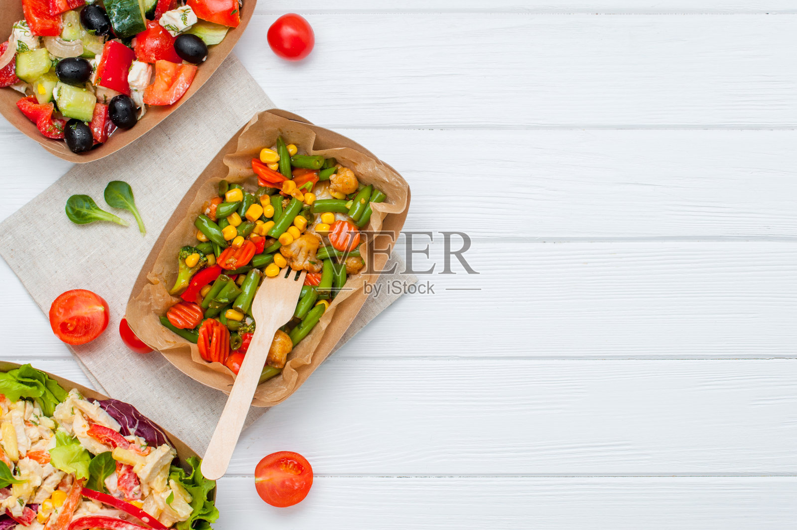 蔬菜沙拉在棕色的牛皮纸食品容器在白色木制背景照片摄影图片