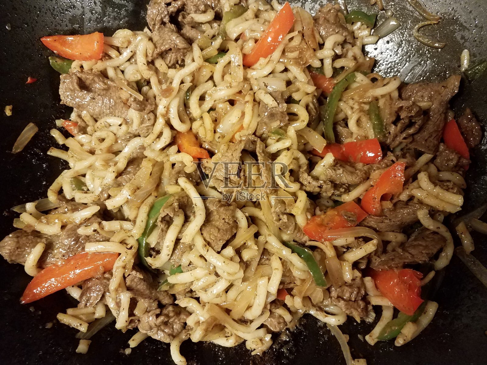 煎锅里的牛肉、面条、青椒和红椒照片摄影图片
