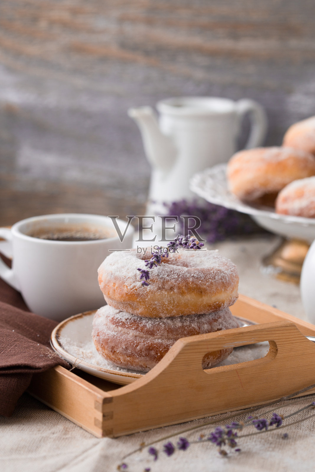 早上的早餐。甜美的自制甜点甜甜圈在乡村设置的木板和一杯咖啡。选择性地专注于前面的甜甜圈。照片摄影图片