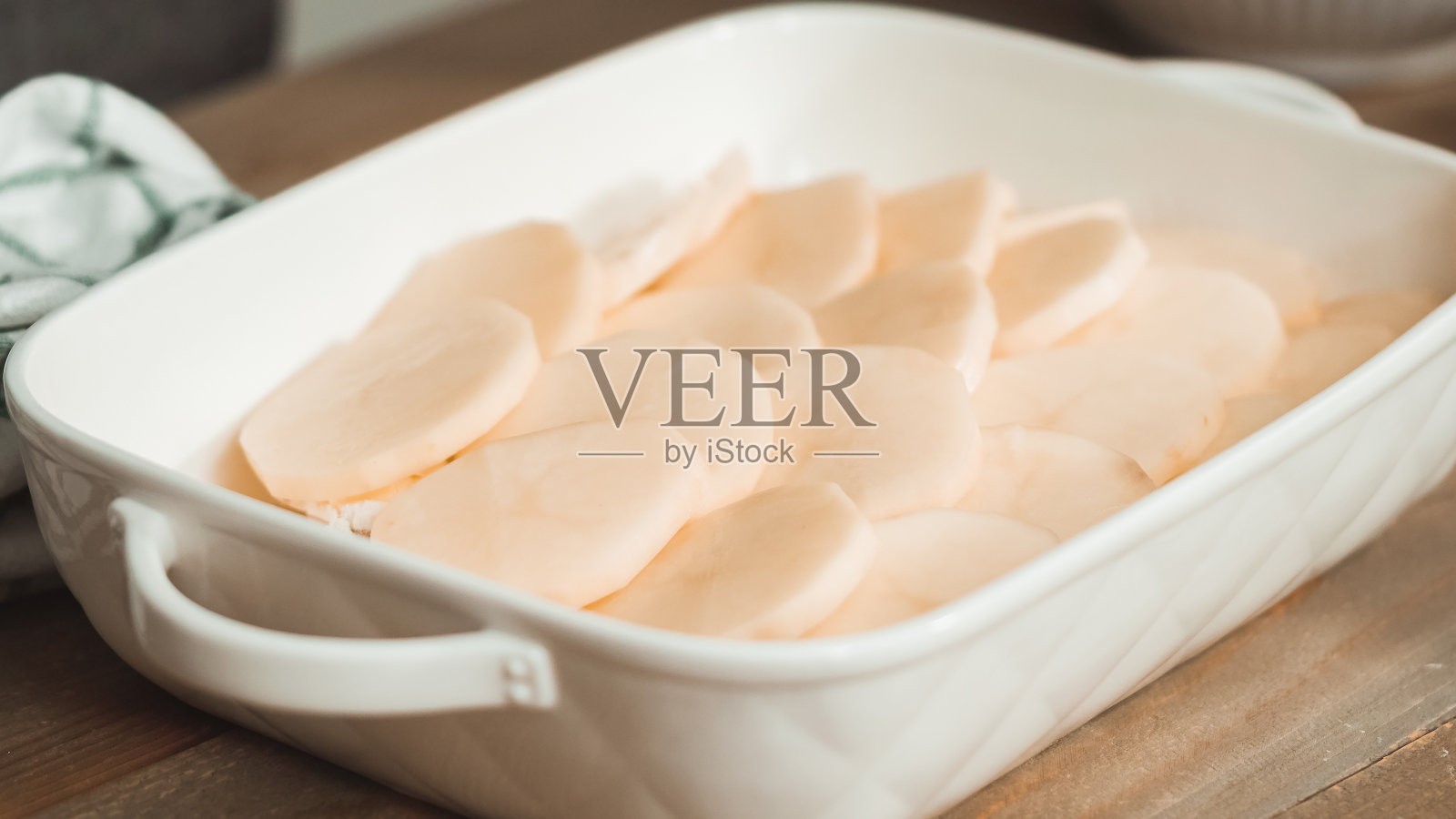 用白色陶瓷烤盘准备土豆扇贝。照片摄影图片