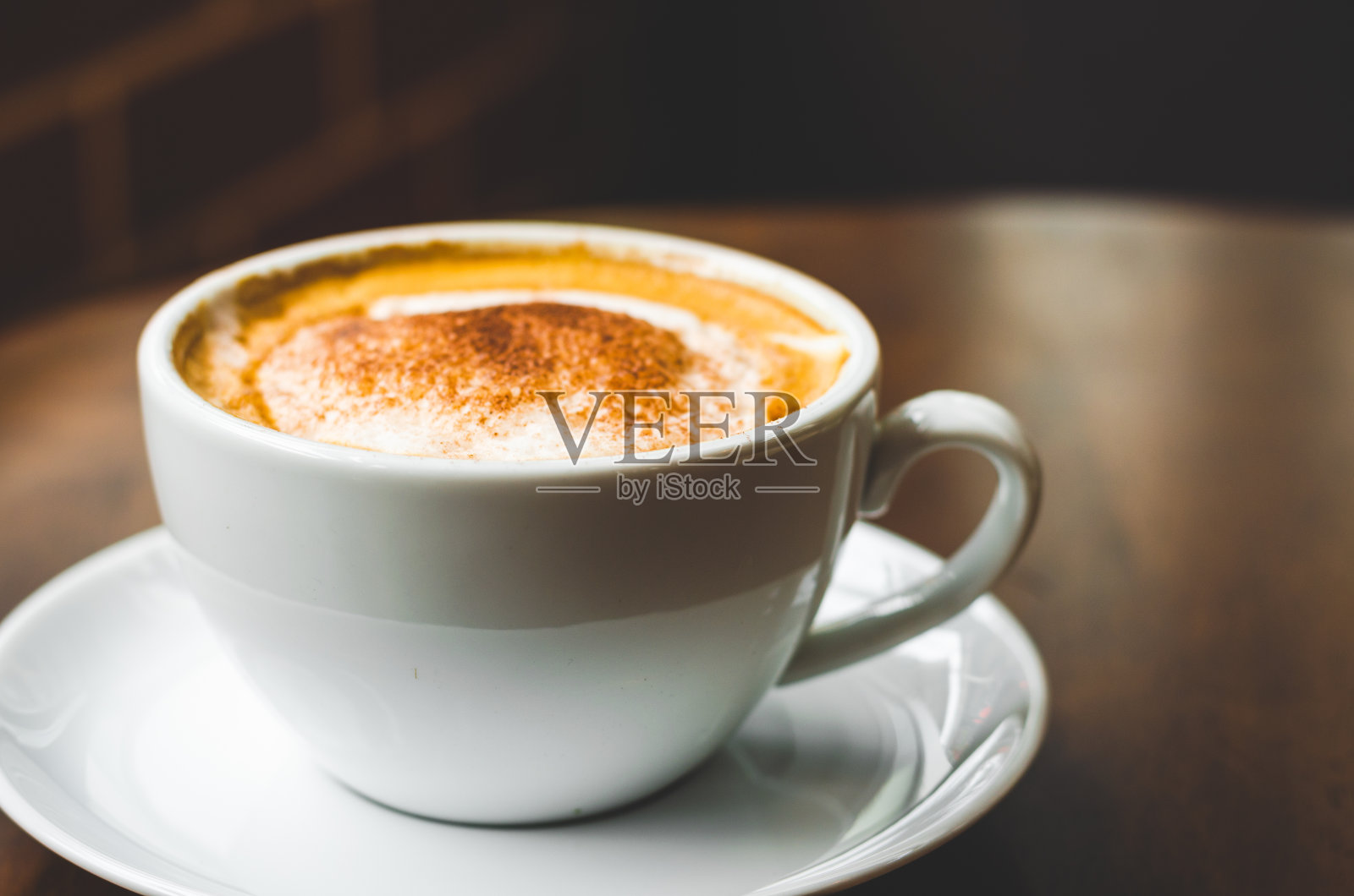 近距离观察现代热黑咖啡，卡布奇诺在木材背景与咖啡泡沫泡沫图案和纹理在白色杯子看起来和感觉如此美味的玻璃桌子在咖啡店。照片摄影图片