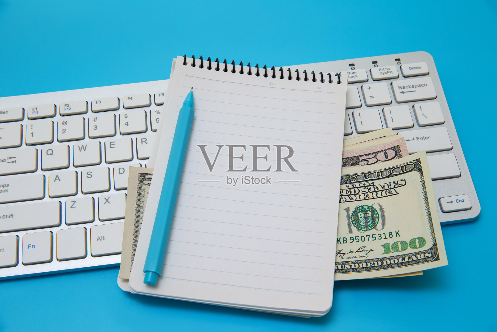 电脑键盘上的空白便条本和美元照片摄影图片