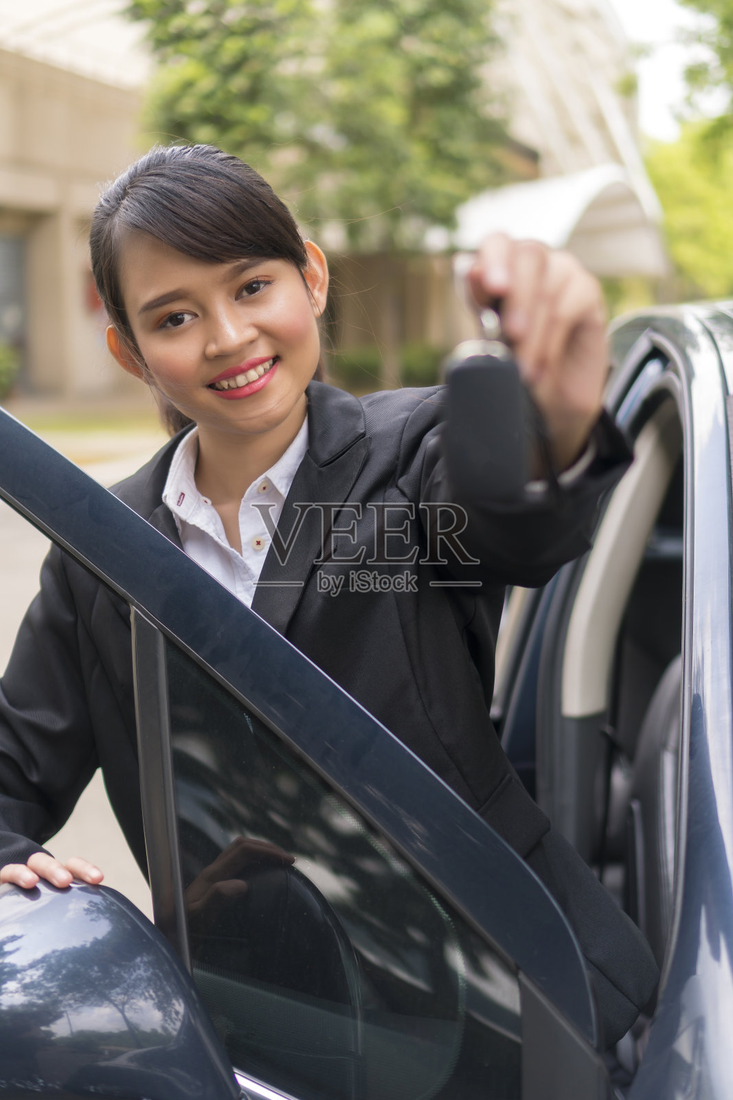 可爱的亚洲女孩拿着车钥匙微笑，网约车概念照片摄影图片