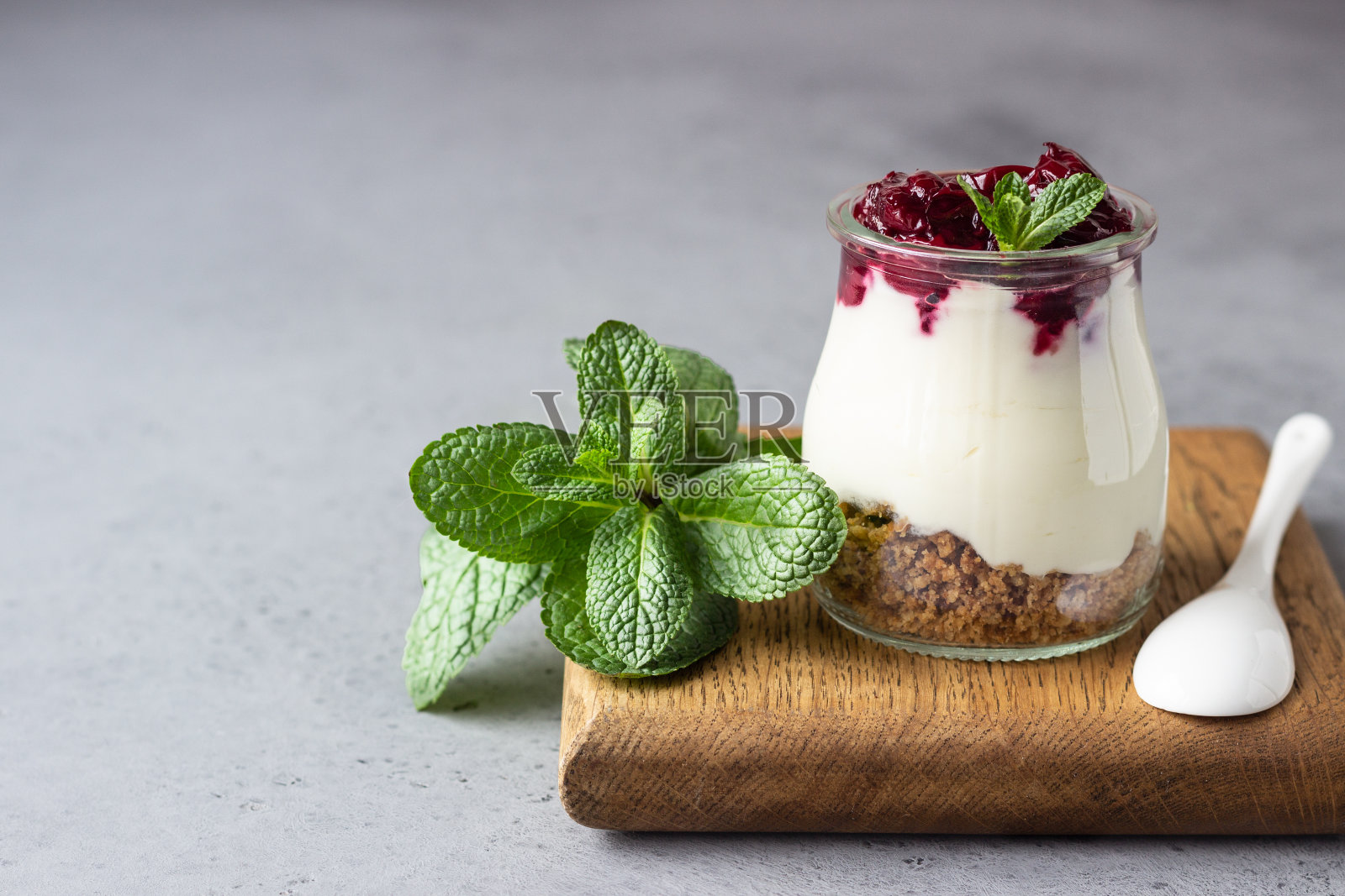 健康的甜点，天然酸奶，饼干，樱桃和薄荷。将甜点放在玻璃杯中。副本的空间。照片摄影图片