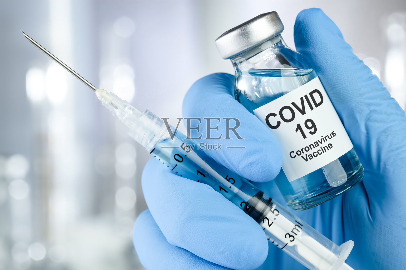 医疗救治理念用一只手拿着蓝色医用手套的冠状病毒、Covid - 19病毒、疫苗瓶照片摄影图片