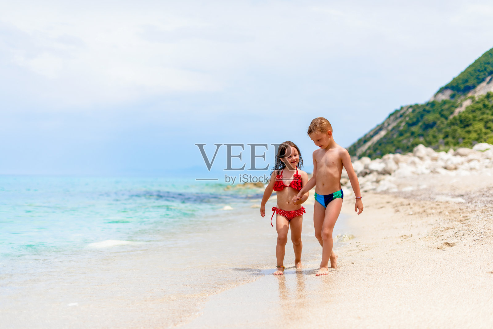 兄妹手牵手在沙滩上散步照片摄影图片