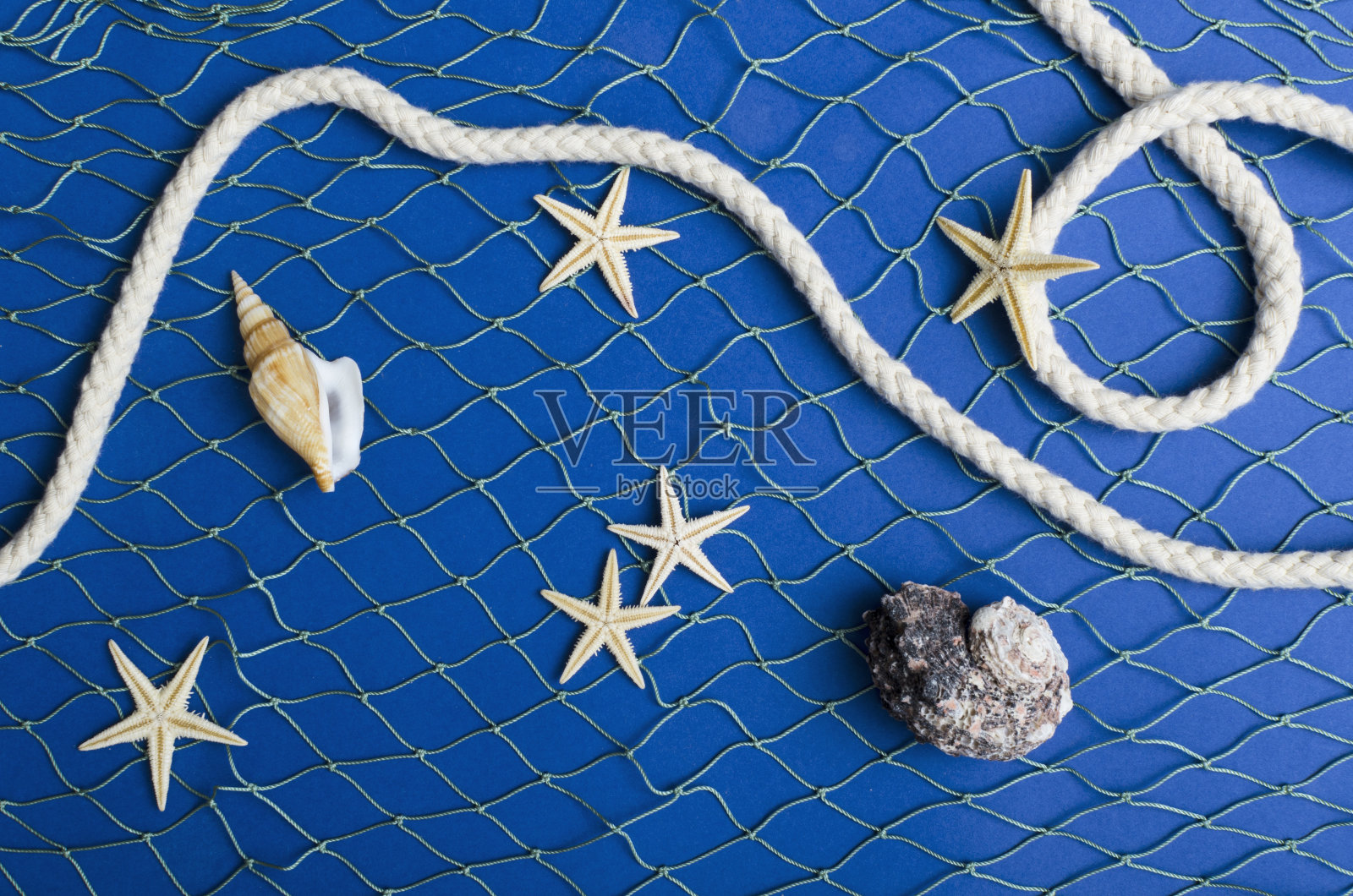 俯视图渔网，海绳和贝壳，上面有海星，深蓝色的背景。暑假季节的概念照片摄影图片