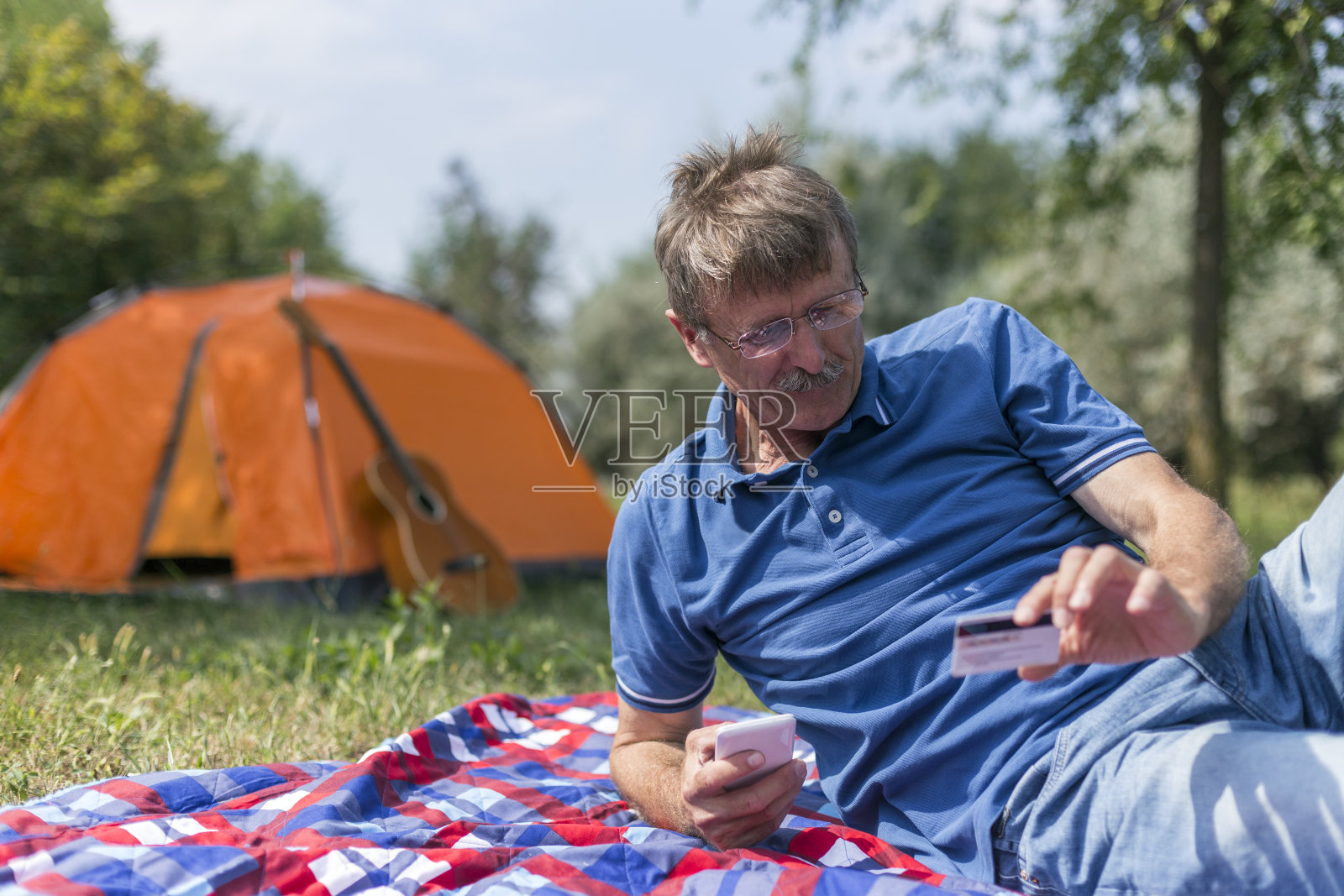 一个成熟的男人在露营时用手机和信用卡照片摄影图片