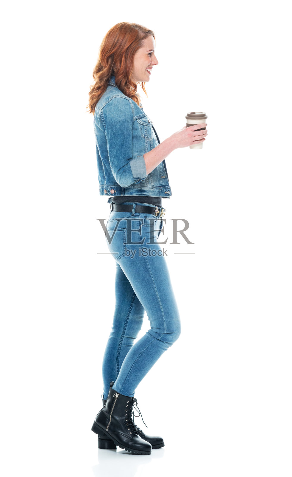 白人女性穿着靴子，拿着咖啡杯站在白色背景前照片摄影图片