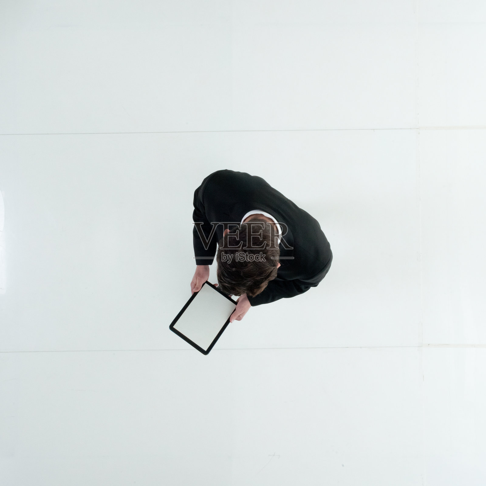 在白色背景前行走的年轻白人男商人，身穿商务装使用触摸屏照片摄影图片