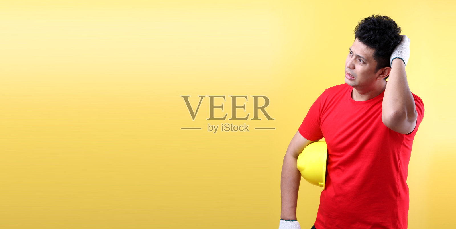 工业工人或工程师在黄色背景工作室研究建筑的肖像，具有复制空间。工作安全概念照片摄影图片