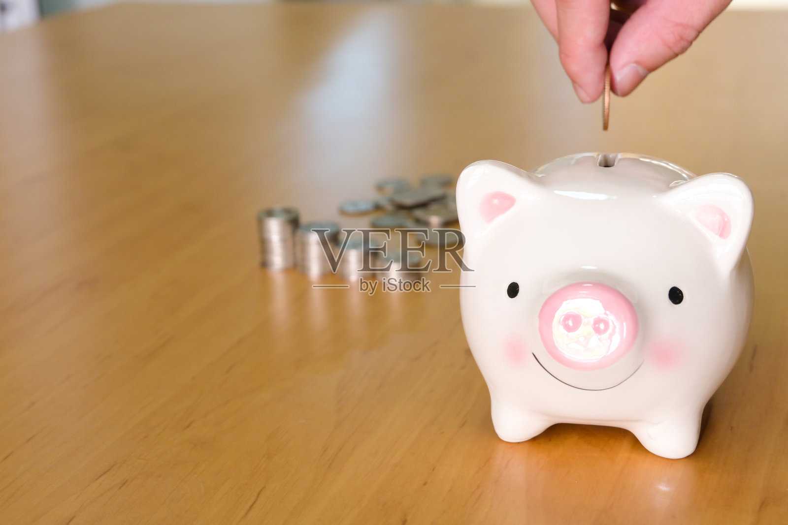 特写：男人将硬币放入存钱罐，用于储蓄和财务规划照片摄影图片