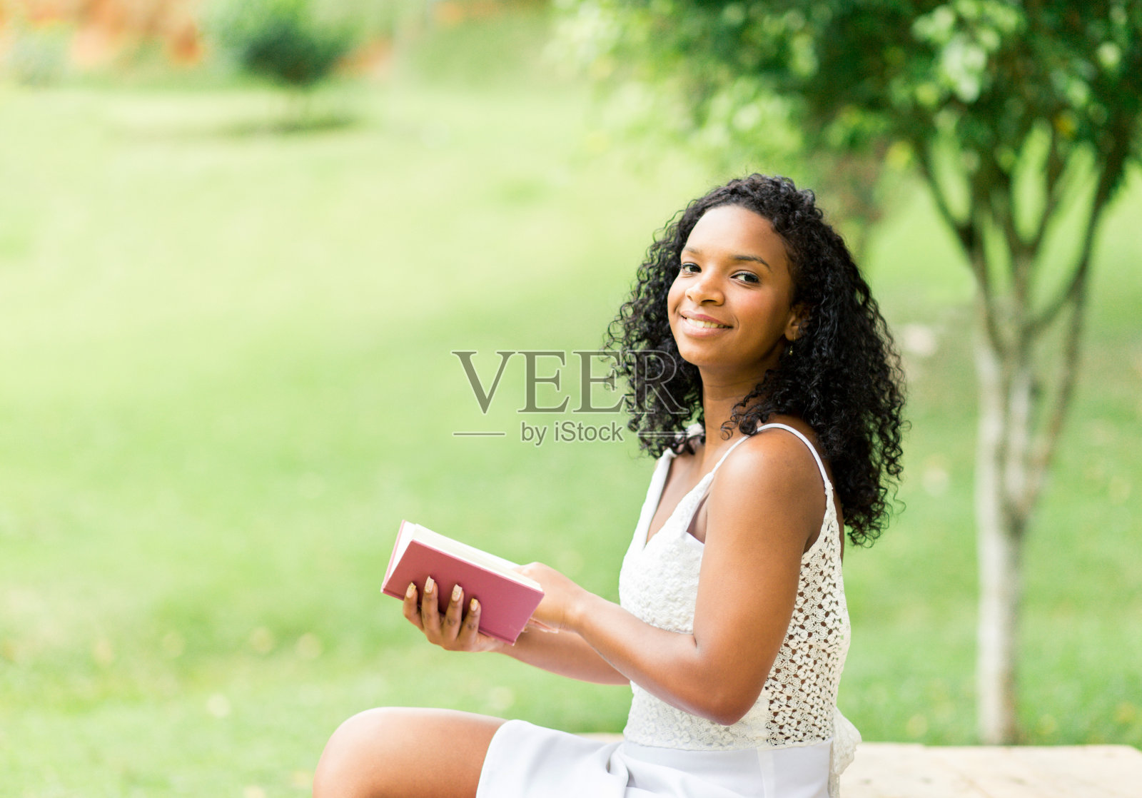 快乐的年轻学生在草地公园里读书照片摄影图片