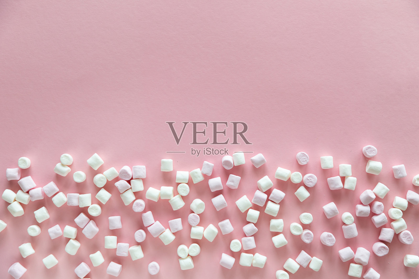 背景或纹理的粉红色和白色的迷你棉花糖在粉红色的背景与自由空间的文本照片摄影图片