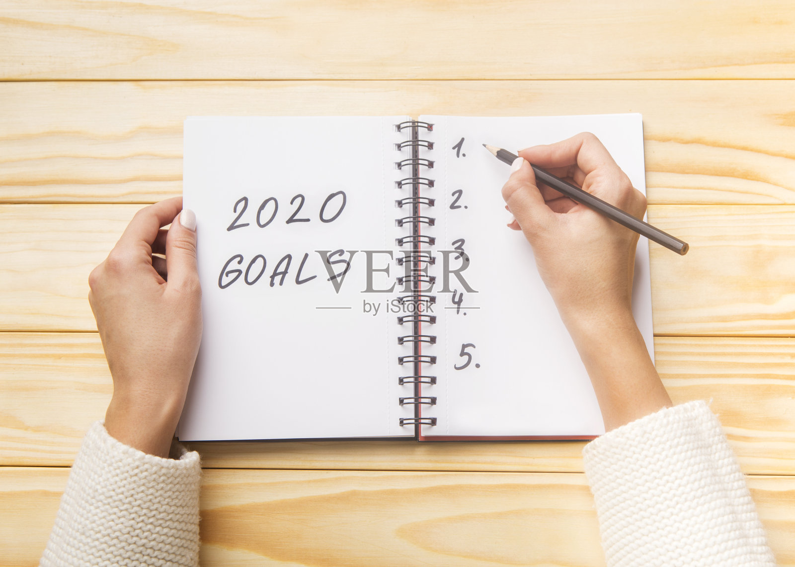 女人用双手在螺旋笔记本上书写2020年目标照片摄影图片