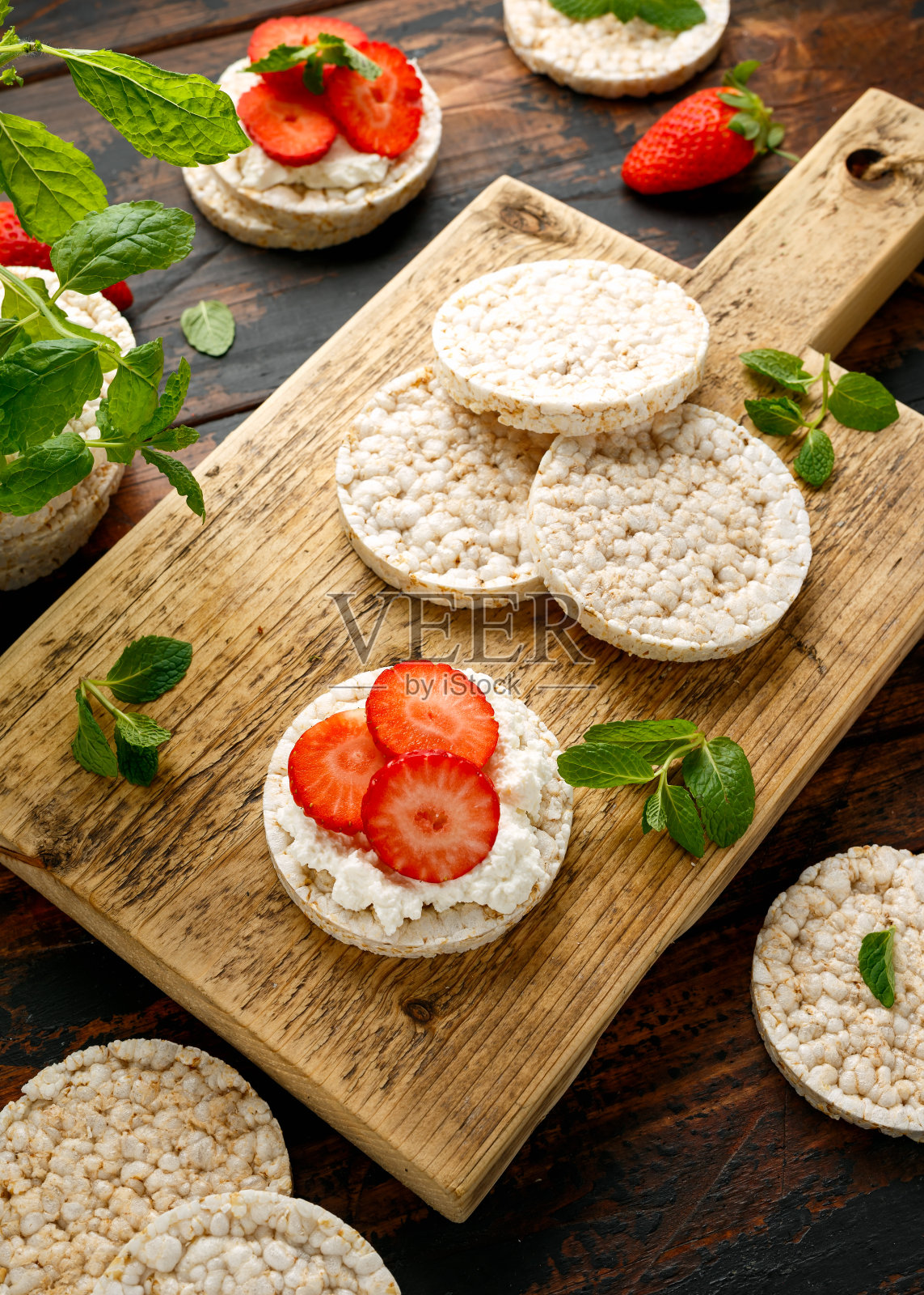 米饼加乳清干酪和草莓放在木板上。健康的食物照片摄影图片
