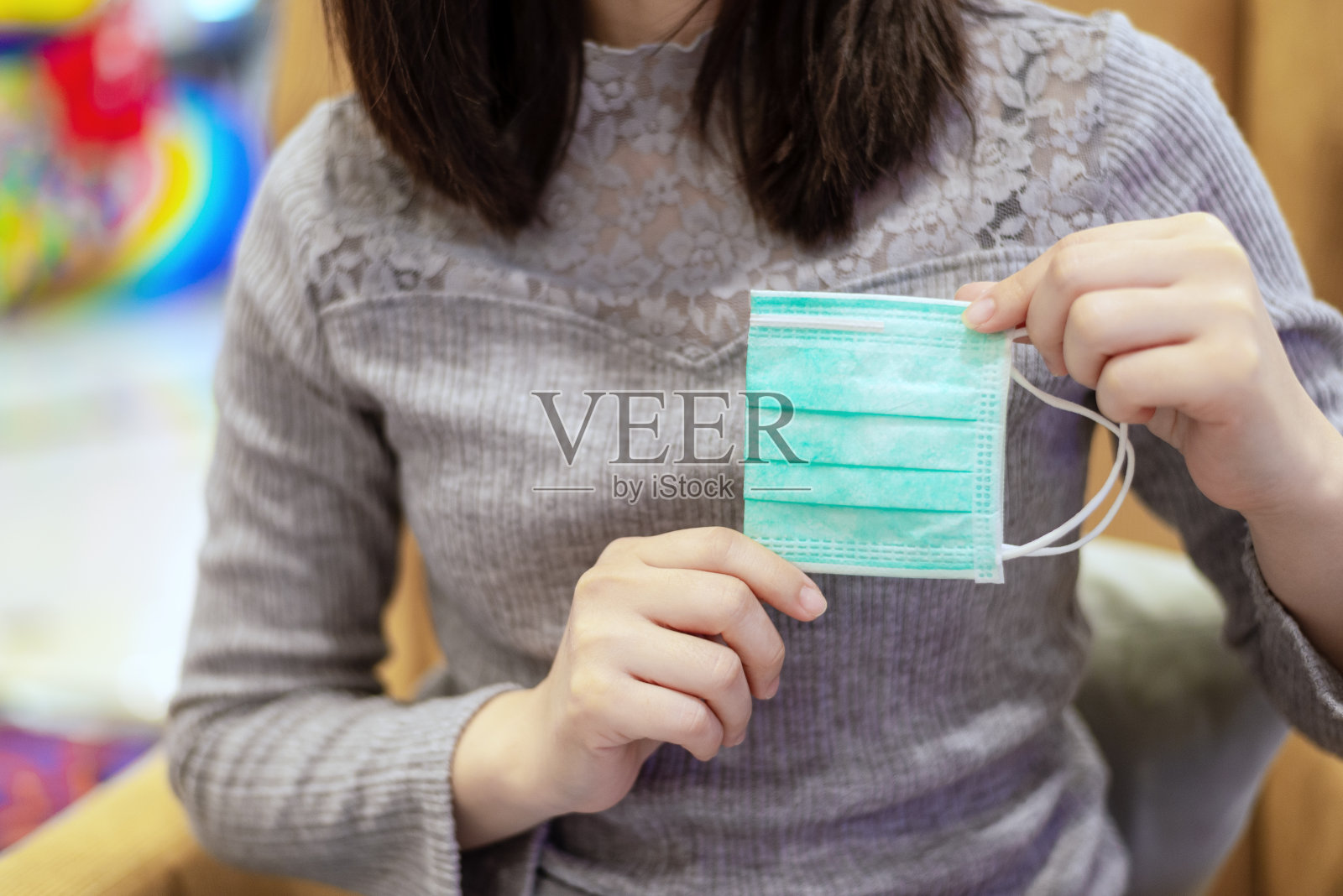 一名妇女双手拿着折叠的医用口罩，展示在佩戴前保护病毒照片摄影图片