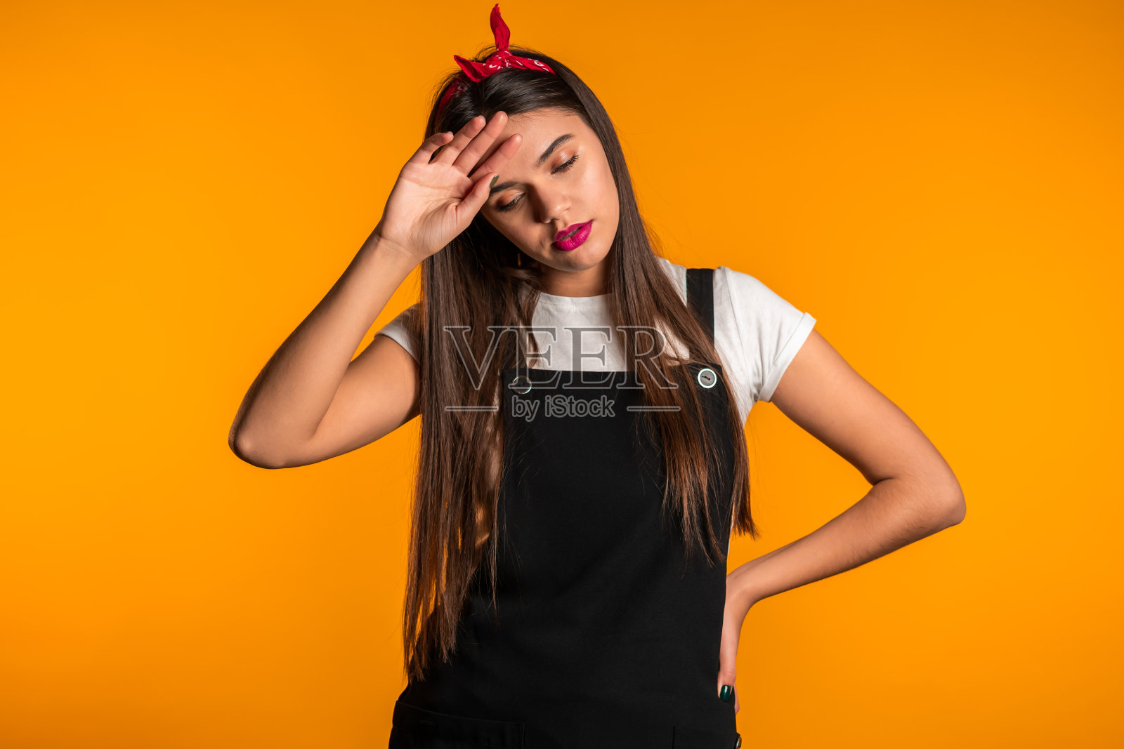 年轻漂亮的长发女人有头痛，画室肖像。女孩把手放在头上，孤立在黄色背景上。问题和头痛的概念。照片摄影图片